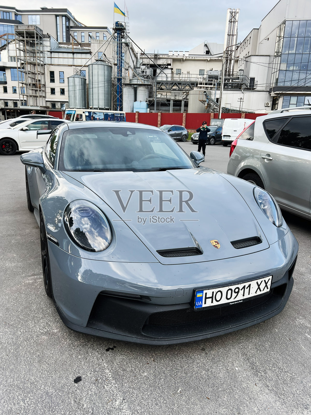 灰色豪华保时捷911 GT3跑车停在户外，天空多云。照片摄影图片