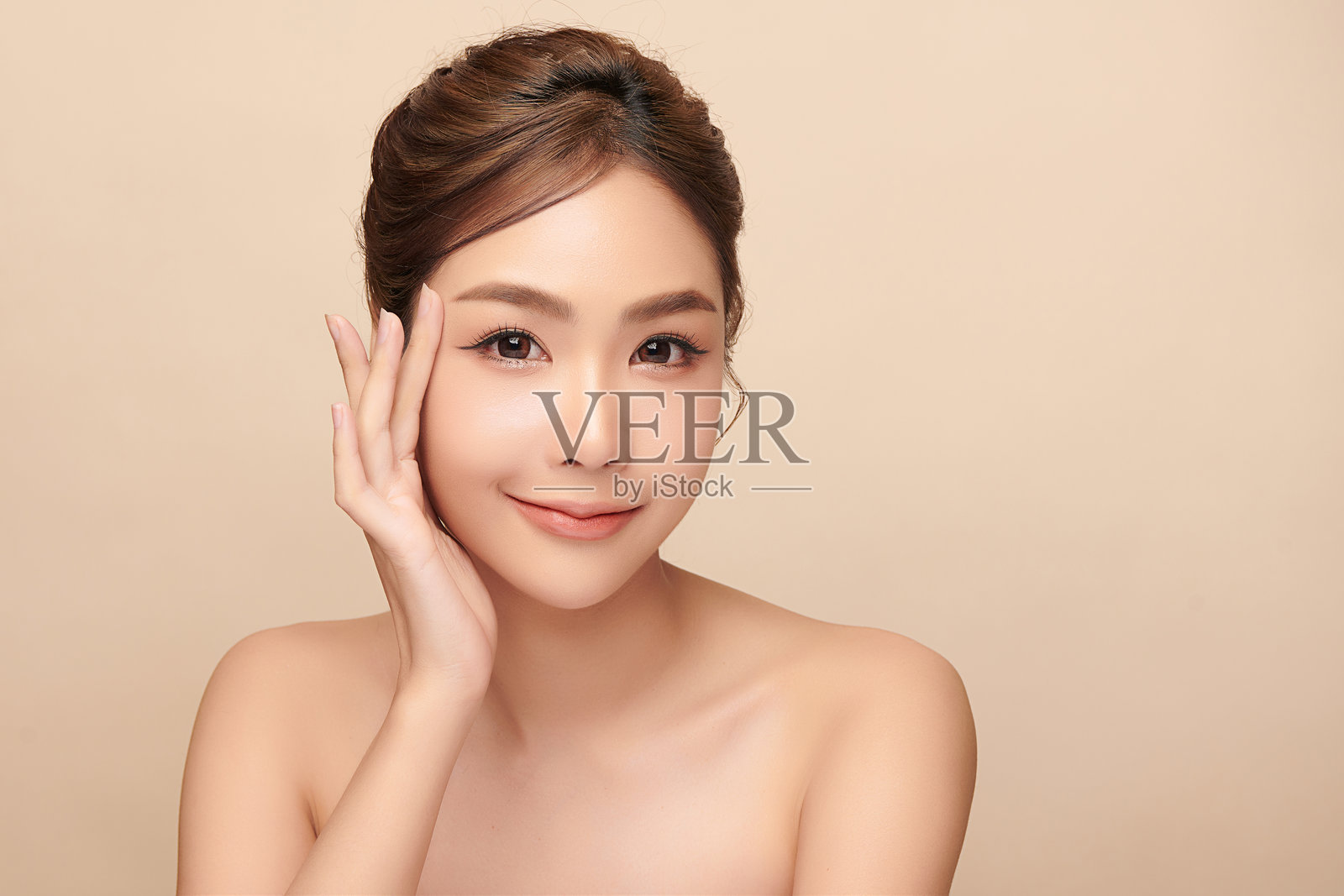 一位年轻美丽的亚洲女性，皮肤洁净清新，背景为米色。护肤、面部护理、美容和水疗。优雅的亚洲女性肖像。照片摄影图片