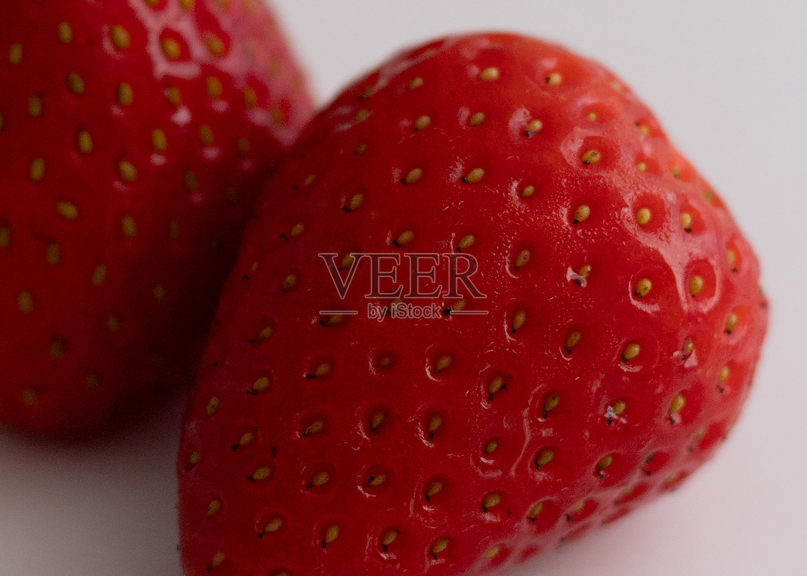 两颗新鲜草莓放在白色表面上照片摄影图片