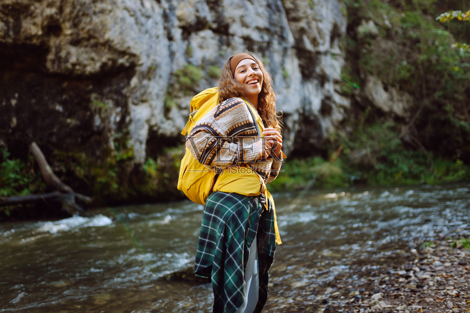 年轻女性背着五彩斑斓的背包，享受着山脉河流附近的美丽风景。照片摄影图片