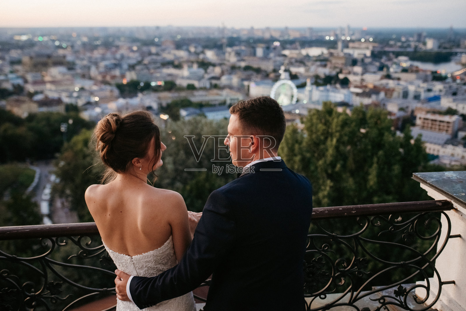 年轻夫妇新娘和新郎在高楼的屋顶上，背景壮观。照片摄影图片