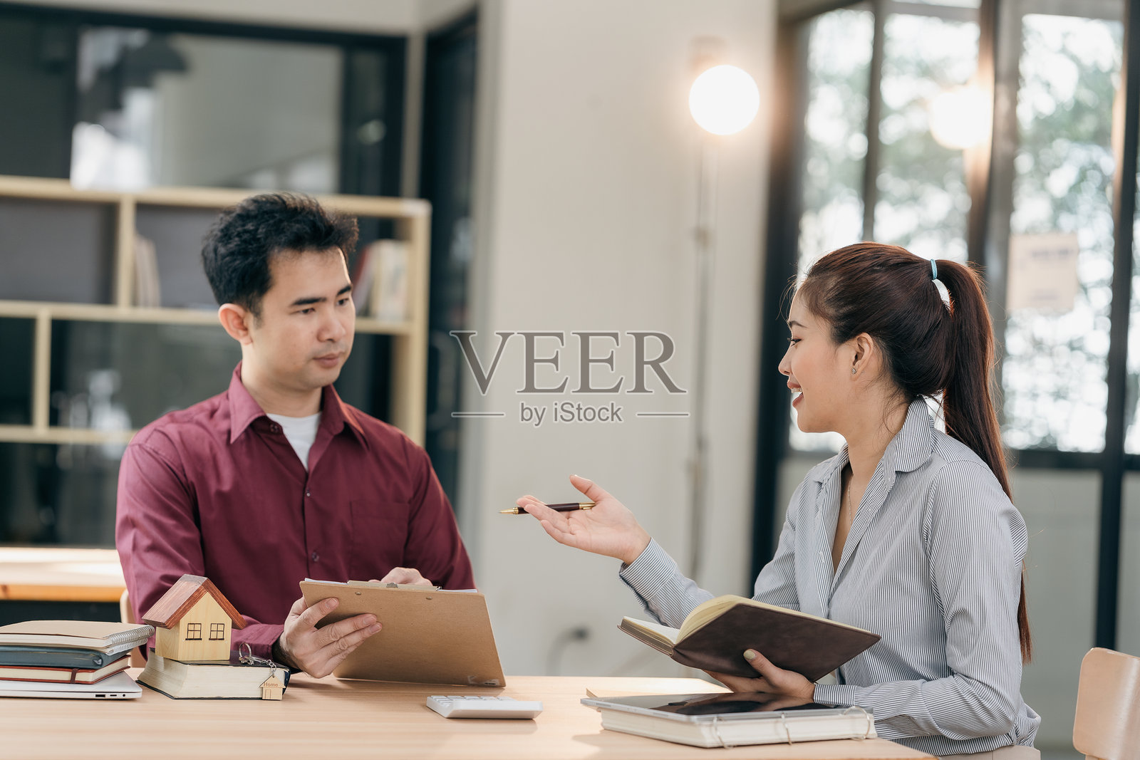 房地产经纪人在会议室向客户展示房屋计划。买家在家庭办公室签署商业合同，并讨论如何在租房、购房贷款或房屋保险上节省开支。照片摄影图片