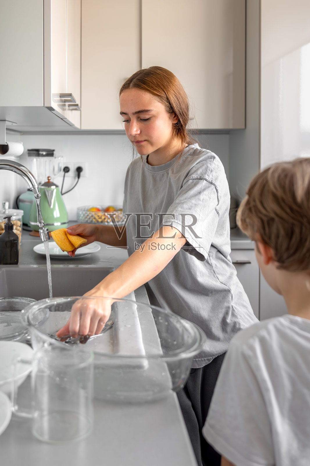 青少年女孩在洗碗。在厨房洗碗。家务。照片摄影图片