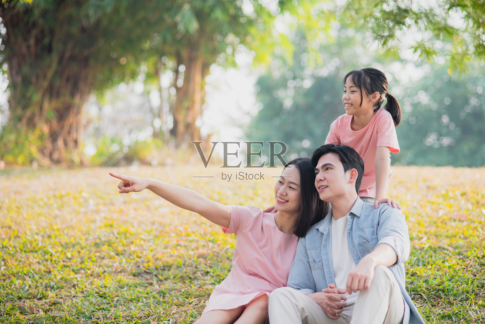 朋友们在公园里享受阳光明媚的一天，微笑着指向地平线。照片摄影图片