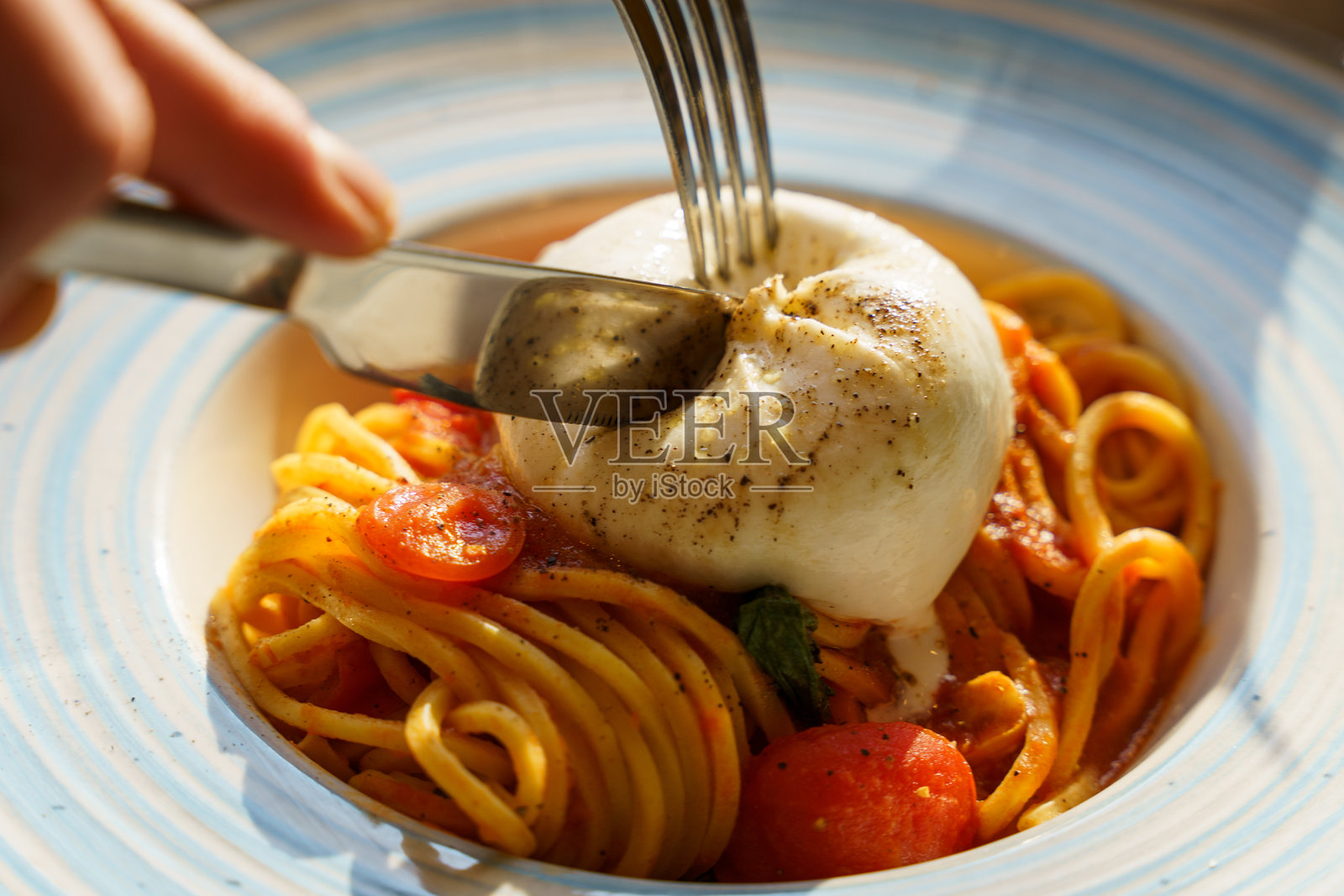 在意大利面上切开布拉塔奶酪，配以番茄酱照片摄影图片