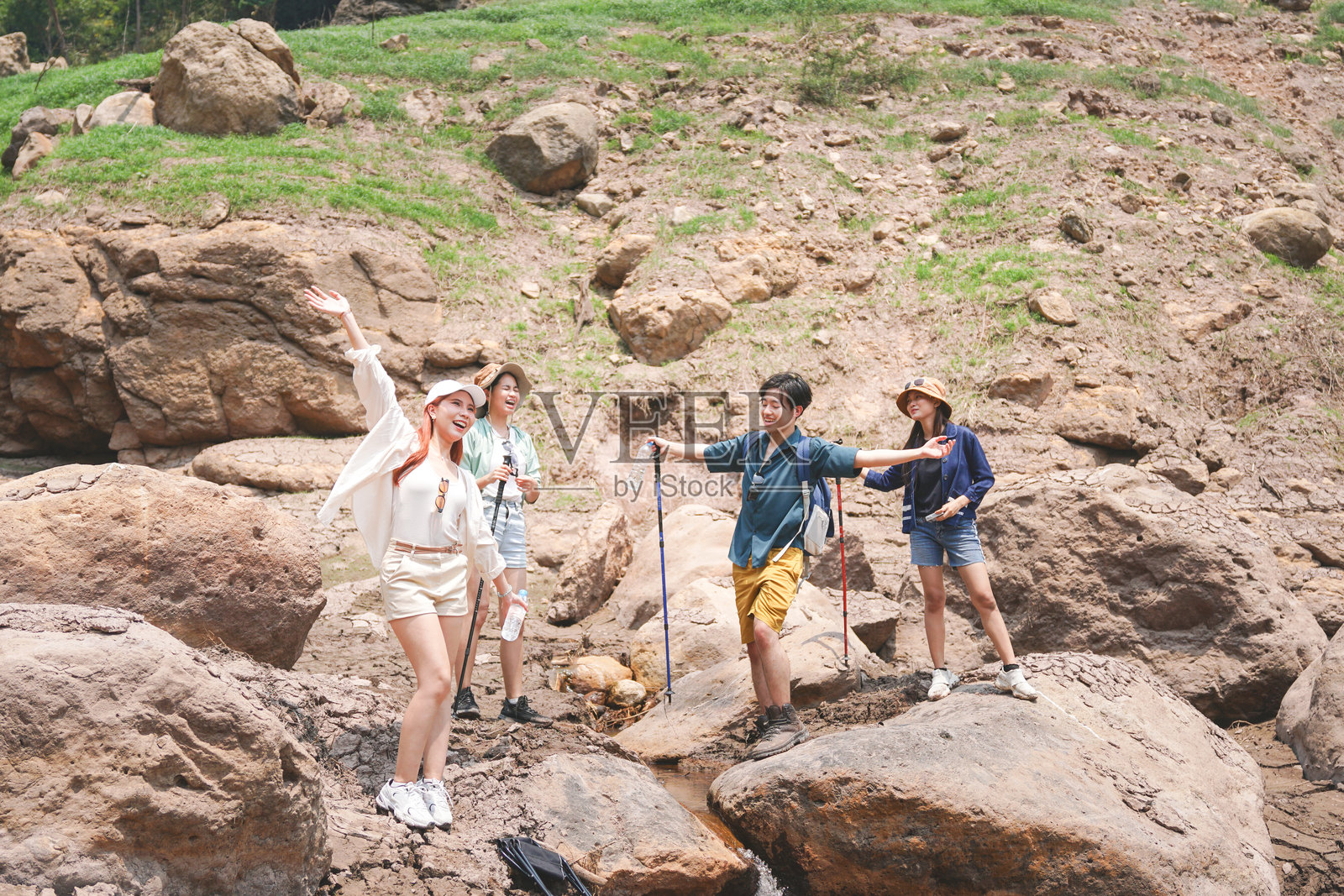 一群朋友在崎岖的地形上享受愉快的徒步旅行，快乐的徒步者在自然风光中摆姿势并挥手，年轻人在夏季冒险中探索户外。照片摄影图片