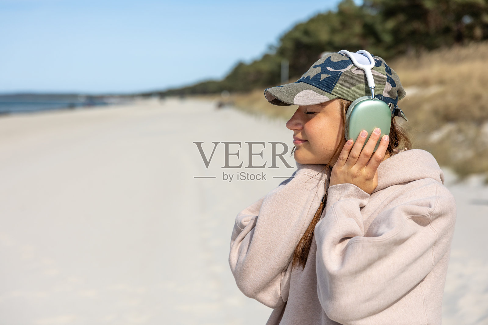 女孩在海边戴着耳机听音乐。户外散步。户外放松。照片摄影图片