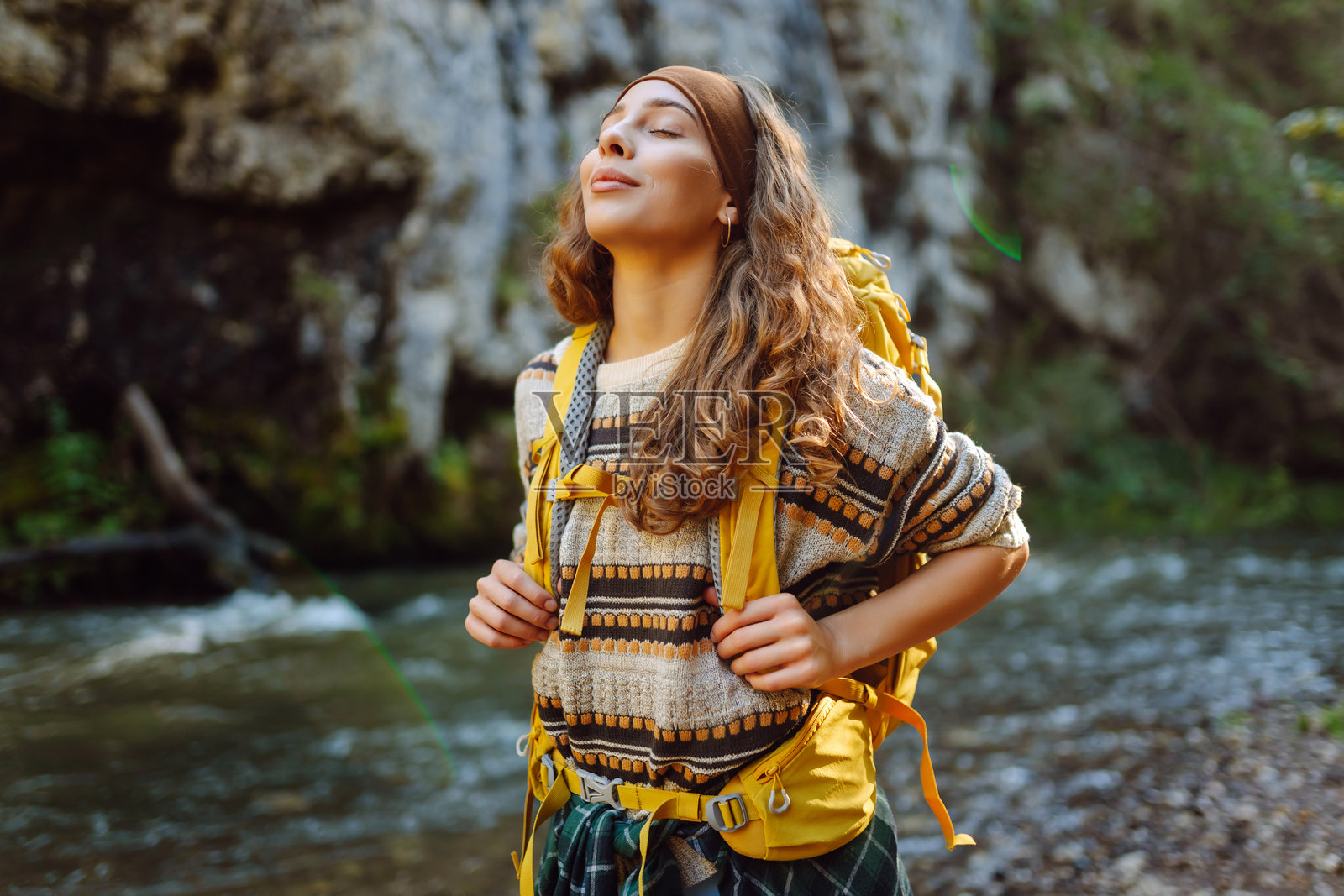 年轻女性背着五彩斑斓的背包，享受着山脉河流附近的美丽风景。照片摄影图片