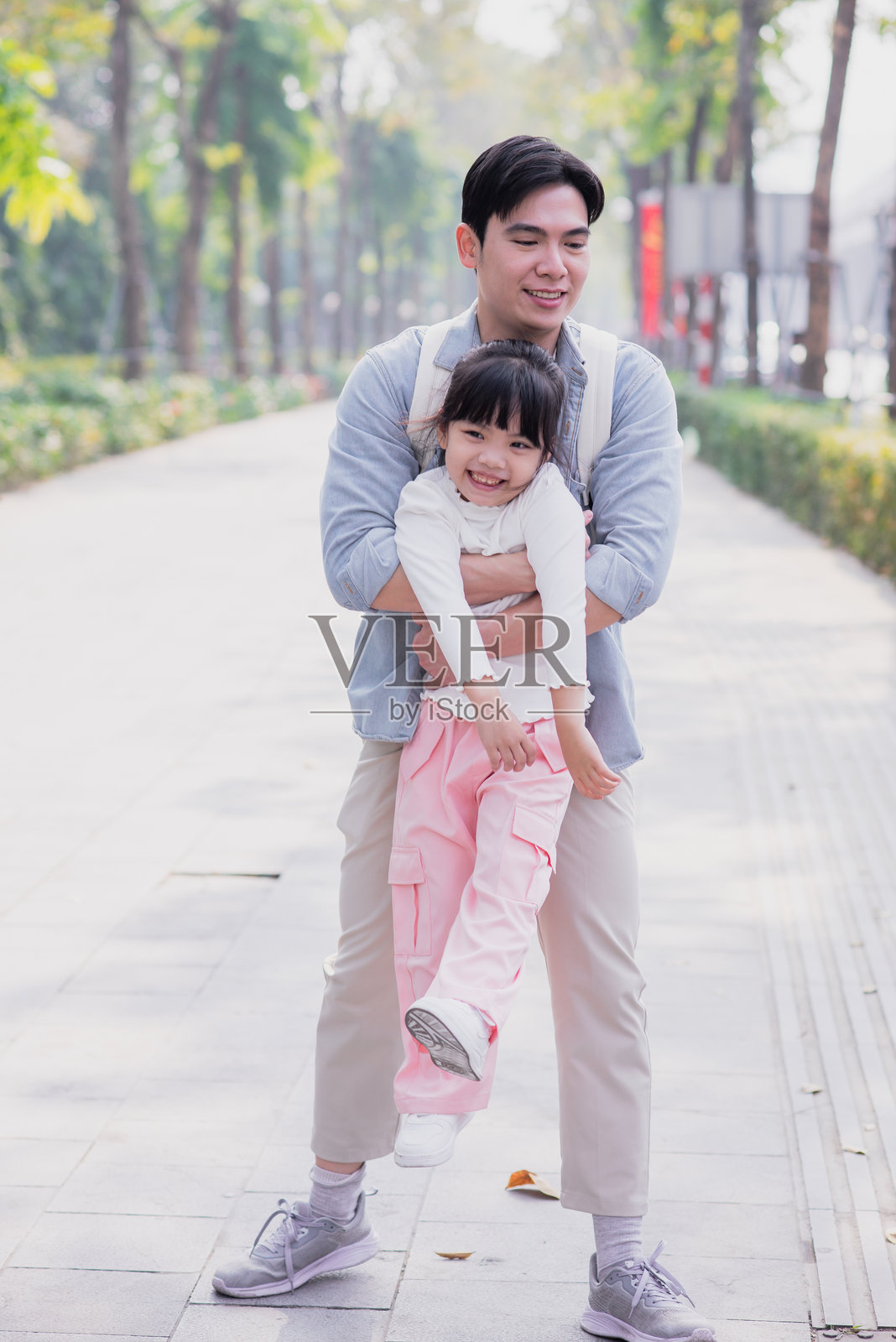 父亲在阳光明媚的公园里与女儿玩耍，两人一起享受美好的时光。照片摄影图片