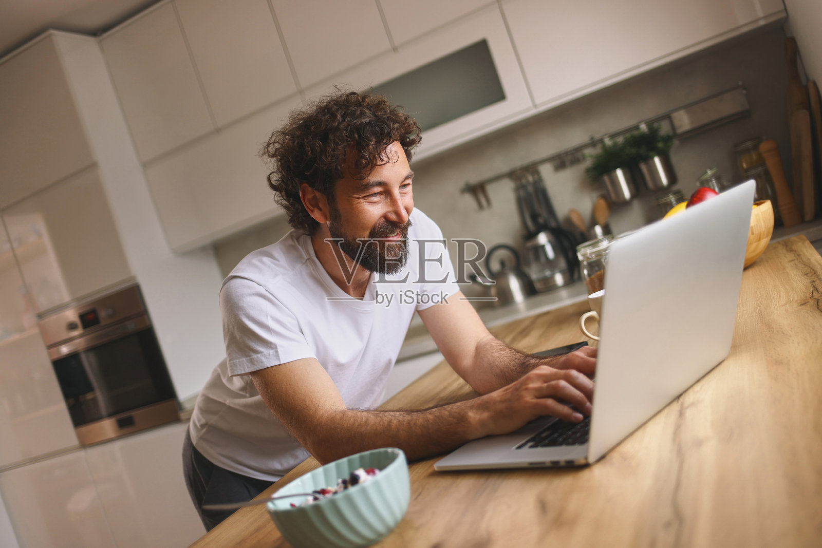 微笑的自由职业者在厨房里使用笔记本电脑远程工作照片摄影图片