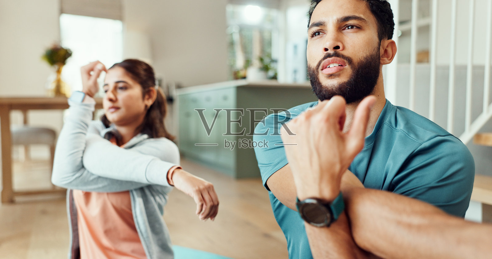 夫妻在家客厅进行锻炼和拉伸，增进感情、健康或共同的幸福。男女人在公寓里为平衡或准备进行健身热身。照片摄影图片