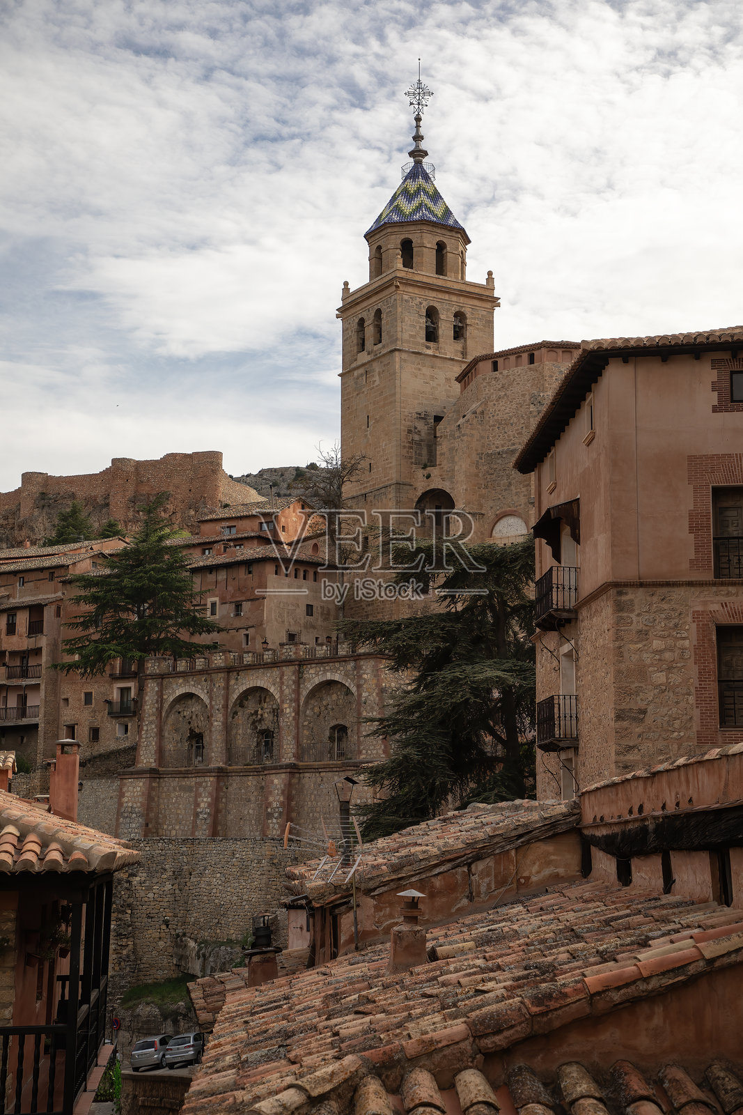 阿尔巴拉辛村历史悠久的教堂钟楼高耸于红陶屋顶和石墙之上照片摄影图片