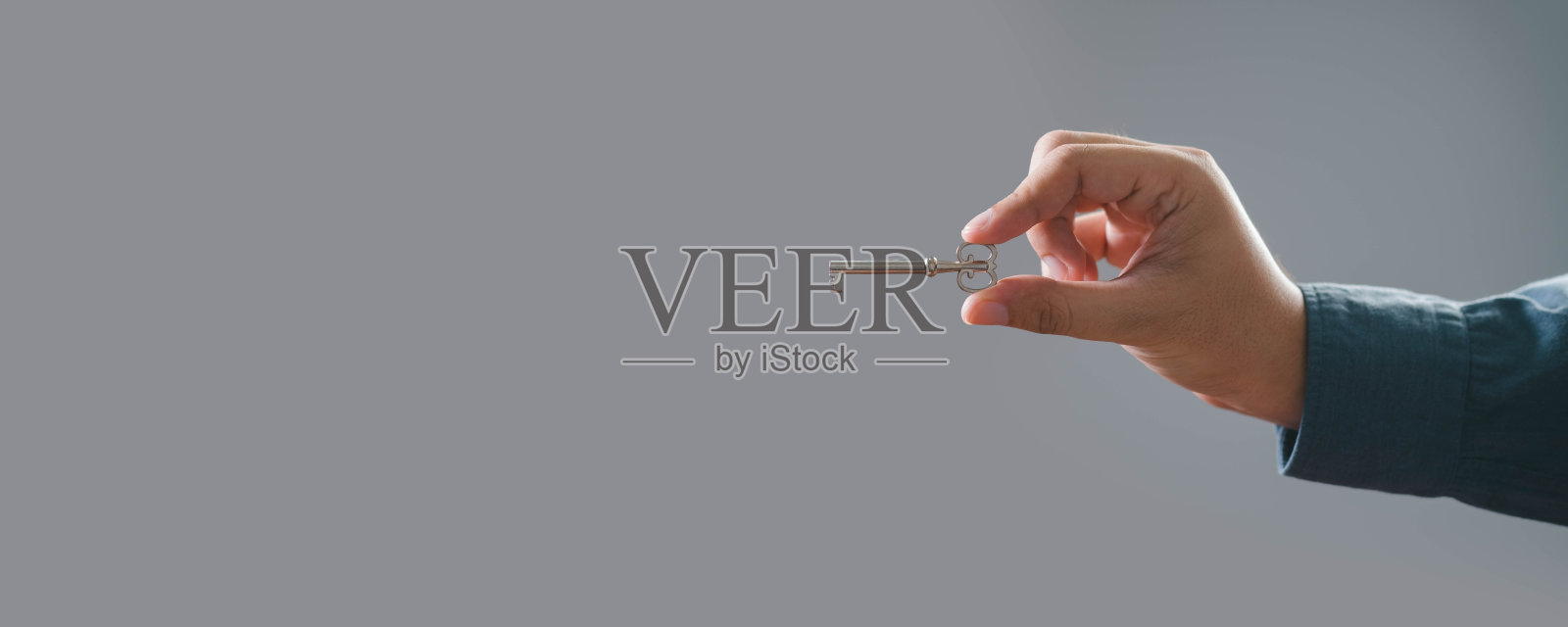 一只手在中性背景下握着一个小物体，象征着在各种情况下的精确和小心处理。照片摄影图片