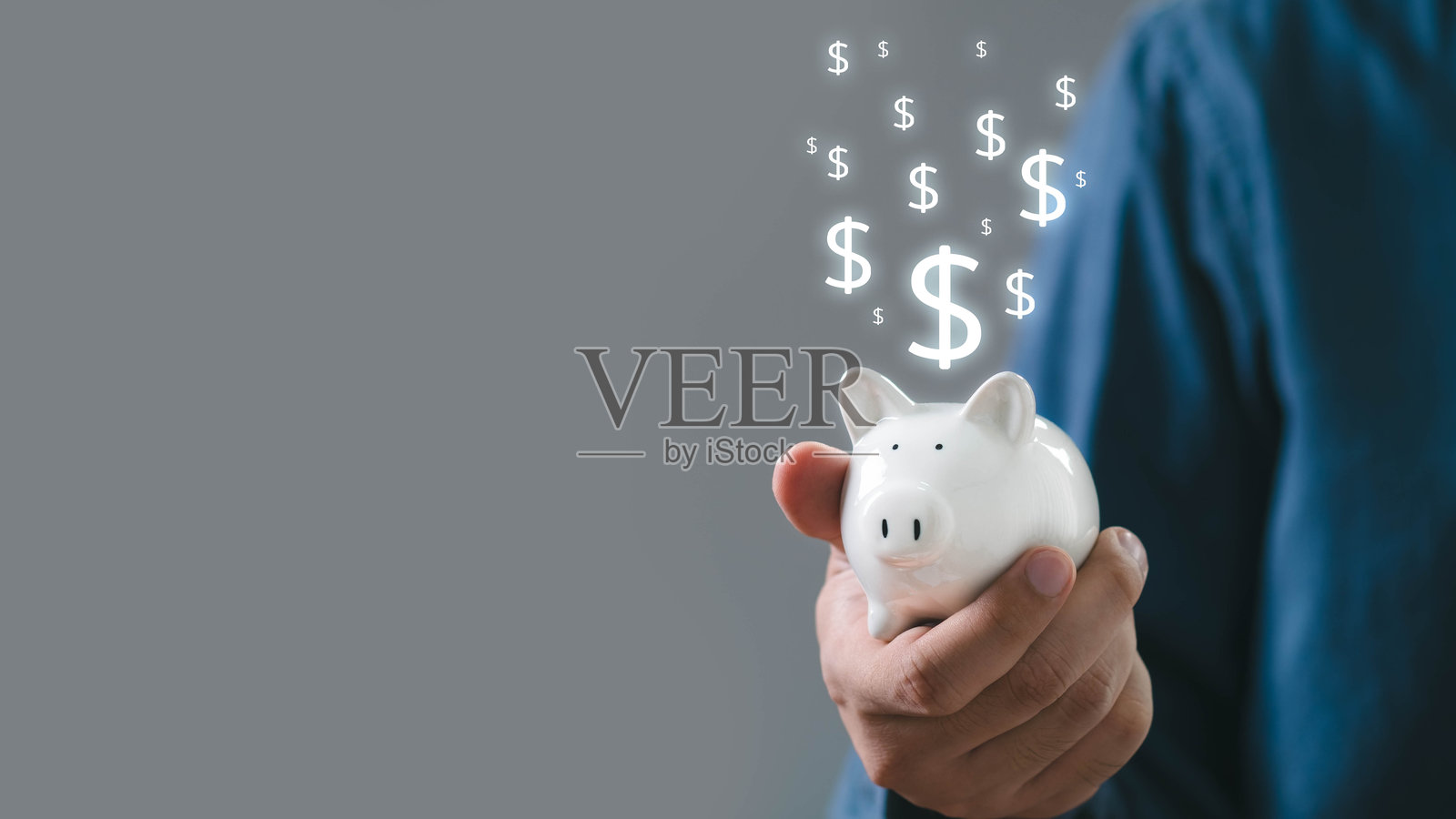 一个人手持一个储蓄罐，上方漂浮着美元符号，象征着储蓄和财务增长。照片摄影图片