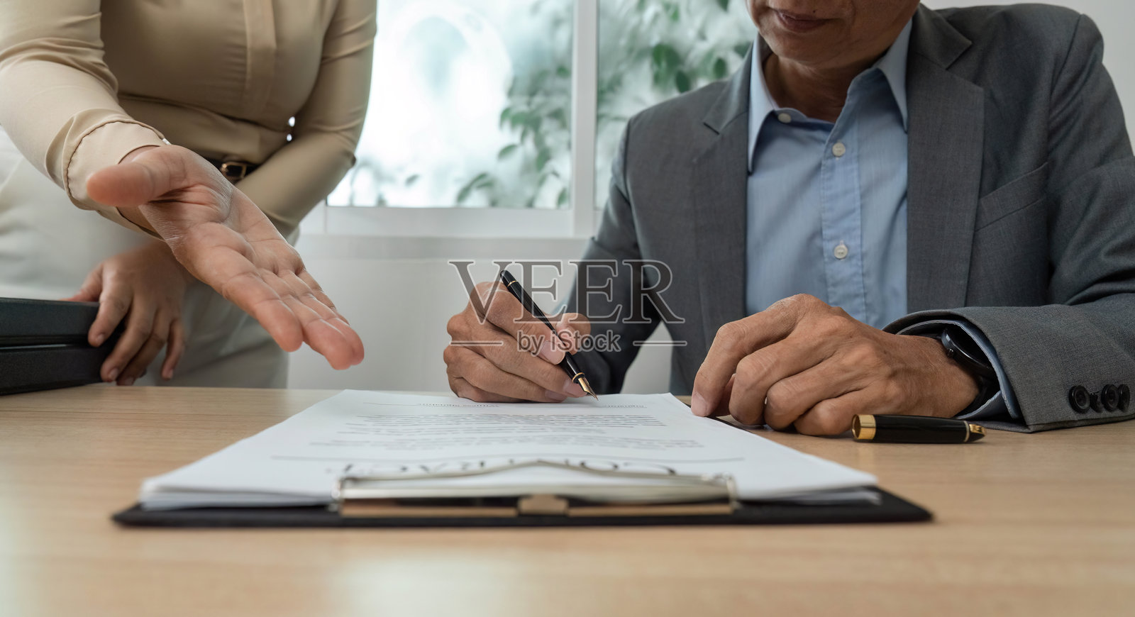 商务协议签署。专业人士在办公桌上签署合同文件。照片摄影图片