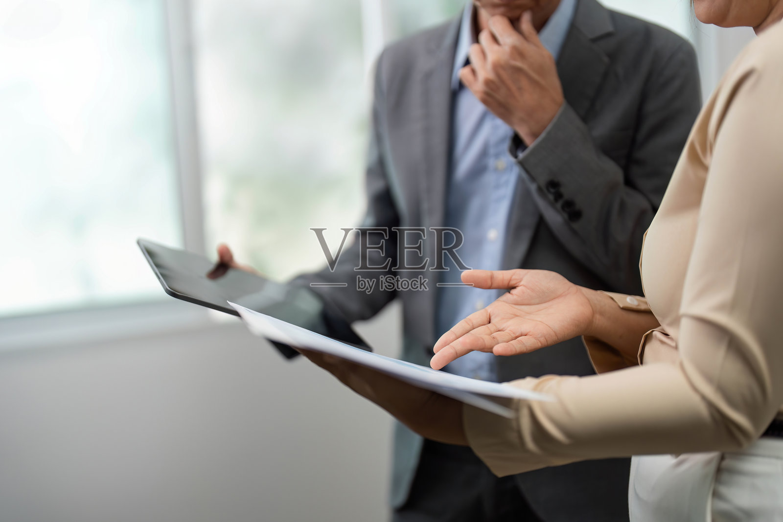 专注的商业分析。同事们在讨论项目细节，手中拿着文件和平板电脑。照片摄影图片