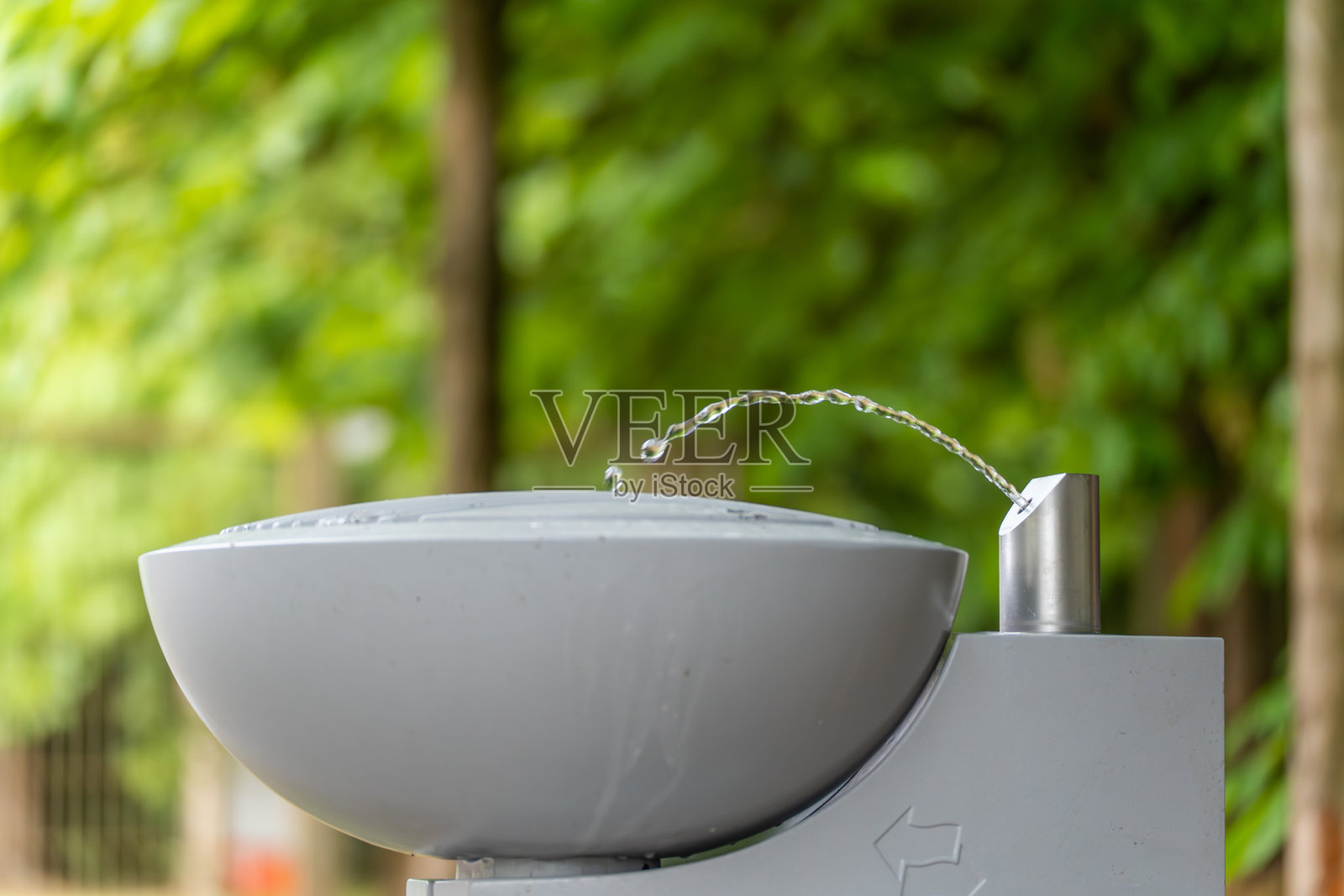 一个现代的户外公共饮水喷泉，水从喷嘴弧形喷出。照片摄影图片