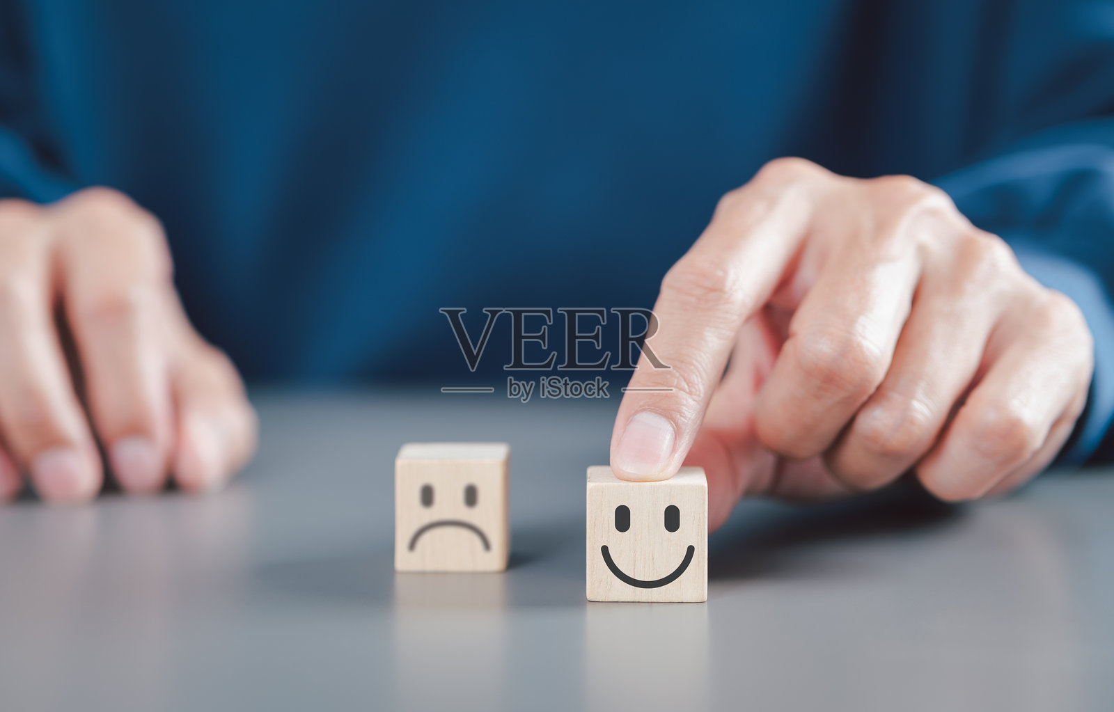 客户满意度与反馈概念。手中选择一个带有笑脸的木块而非悲伤的木块，代表客户满意度、反馈和积极的体验评估。照片摄影图片