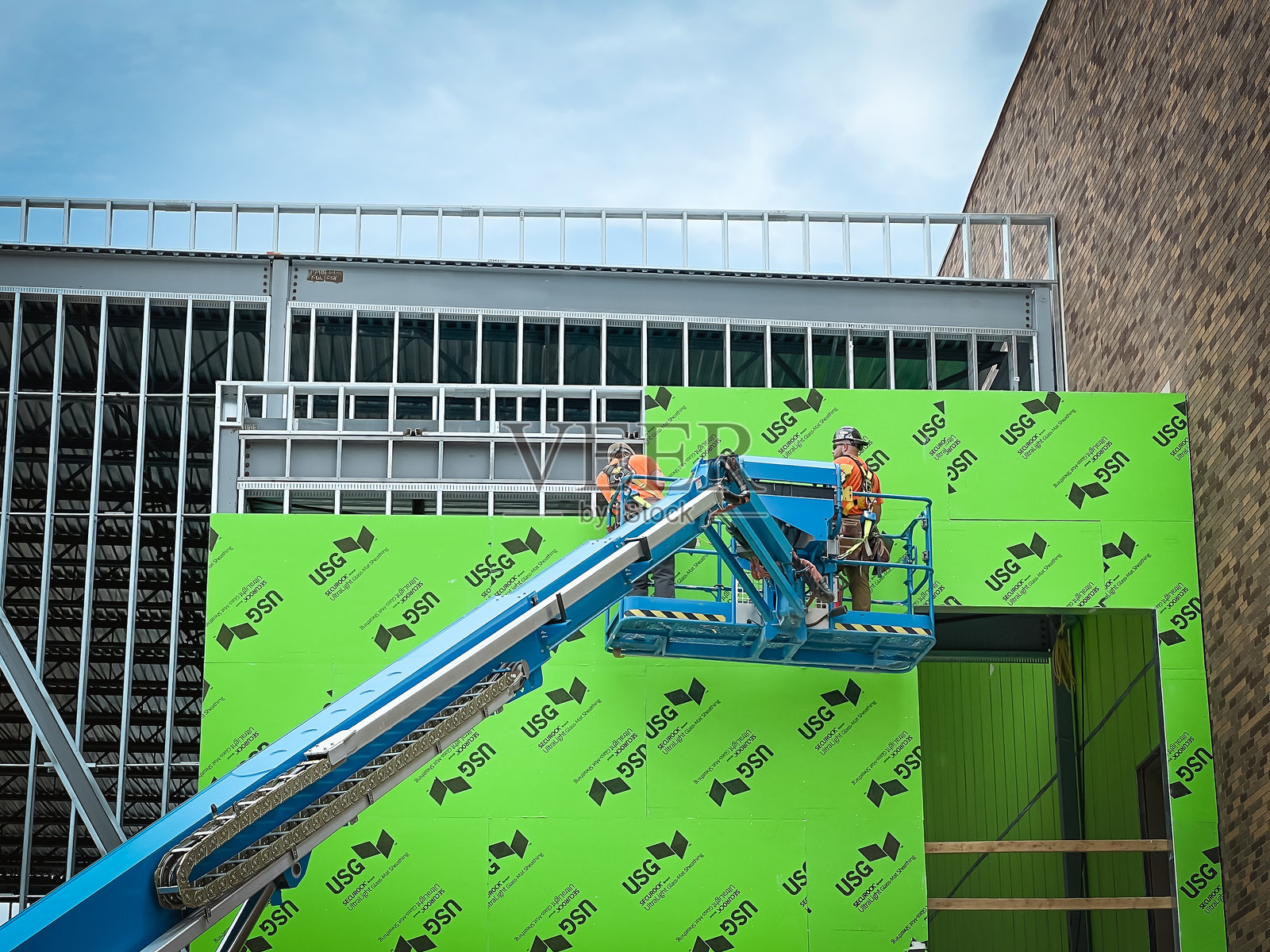 建筑工人在安装外部绿色护墙板照片摄影图片