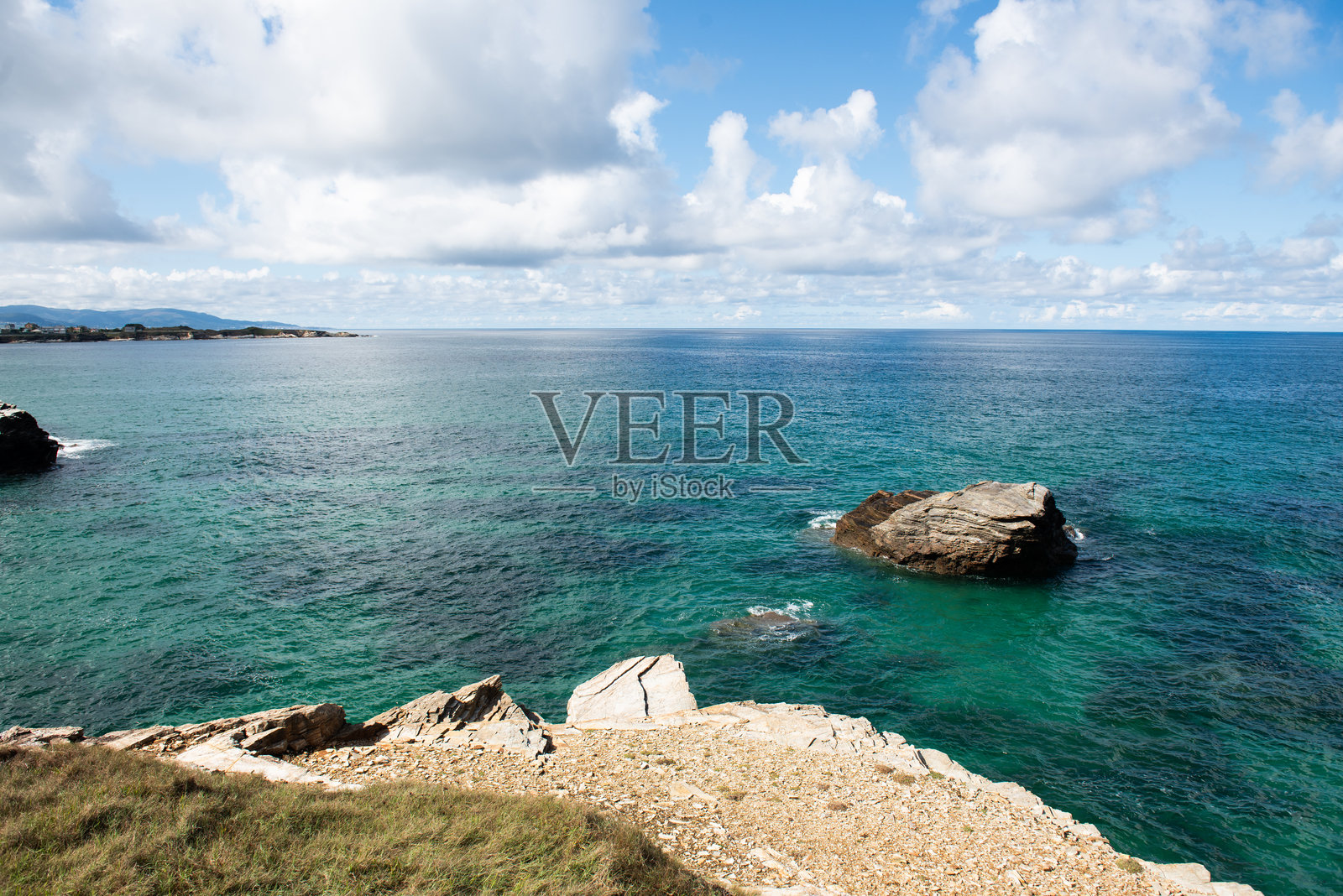 风景如画的海岸线，岩石海岸、清澈的碧蓝海水和天空中的戏剧性云彩，营造出宁静而美丽的自然景观照片摄影图片