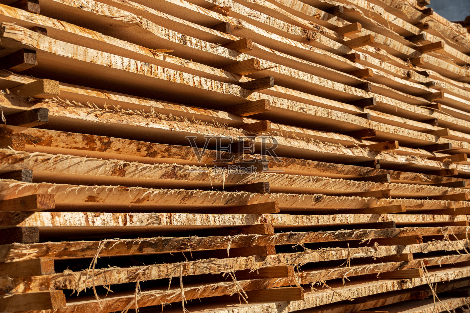 整齐堆放的木板在木材场中展示了自然纹理和纹路在明亮阳光下的美丽。照片摄影图片