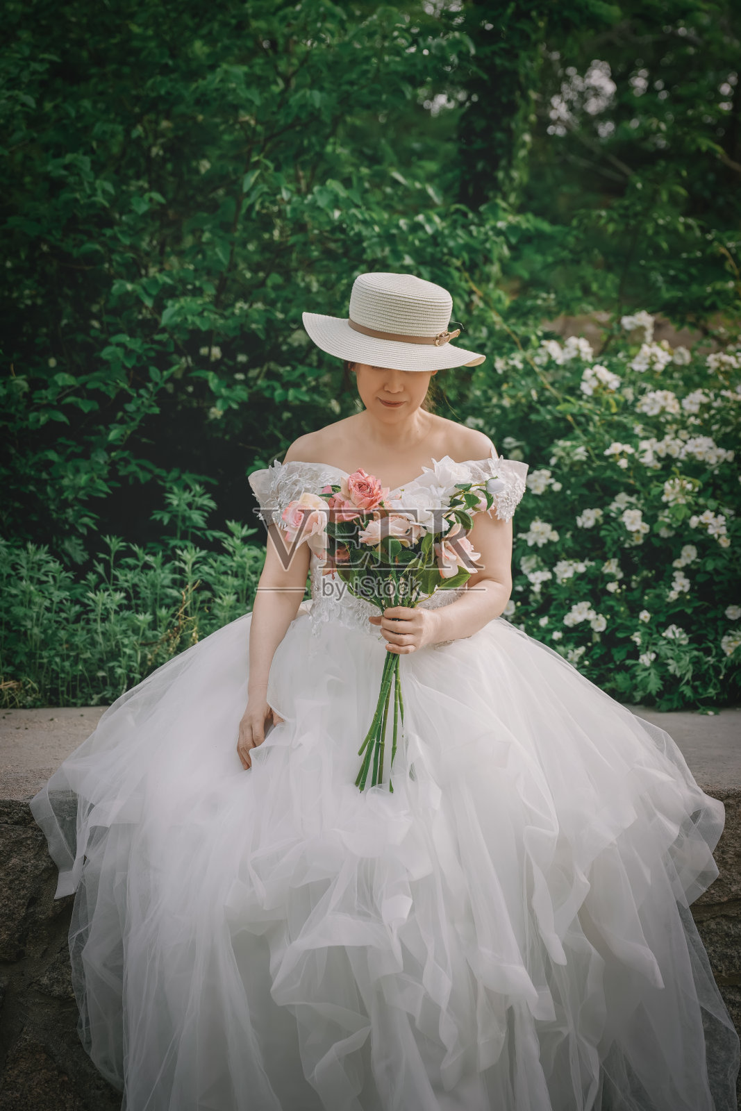 优雅的新娘在公园环境中手捧花束照片摄影图片