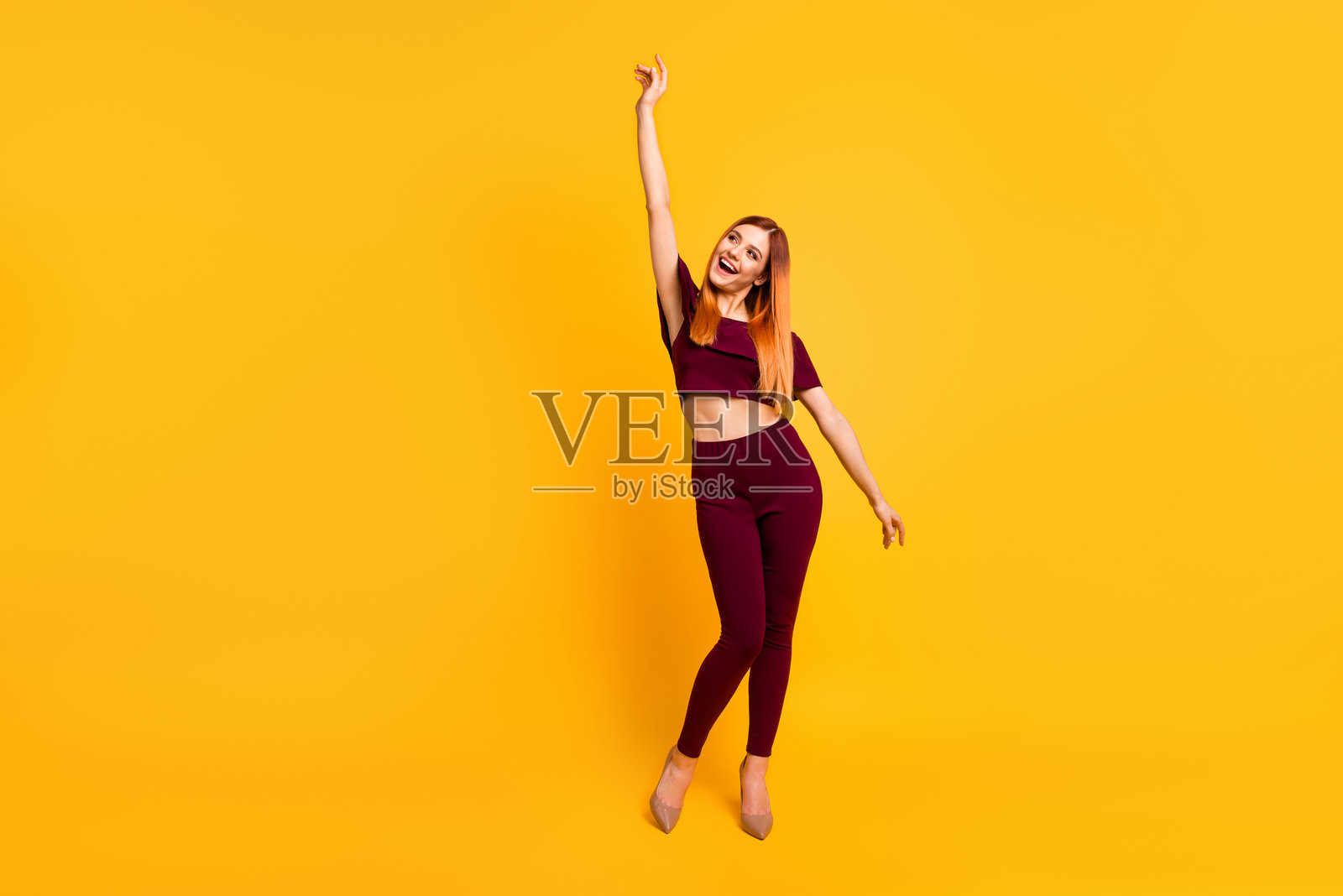 全身照，快乐的漂亮女士在黄色背景下享受舞蹈，心情愉悦。照片摄影图片