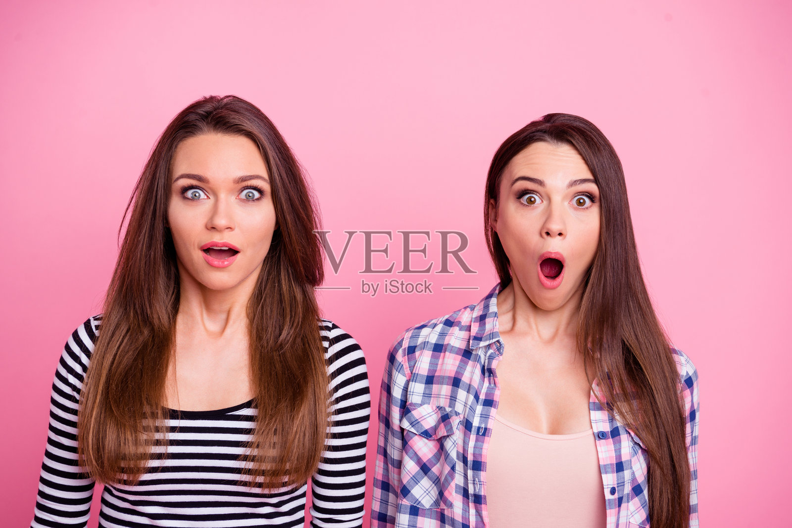 惊讶的女孩们张嘴看向镜头，背景为粉色。照片摄影图片