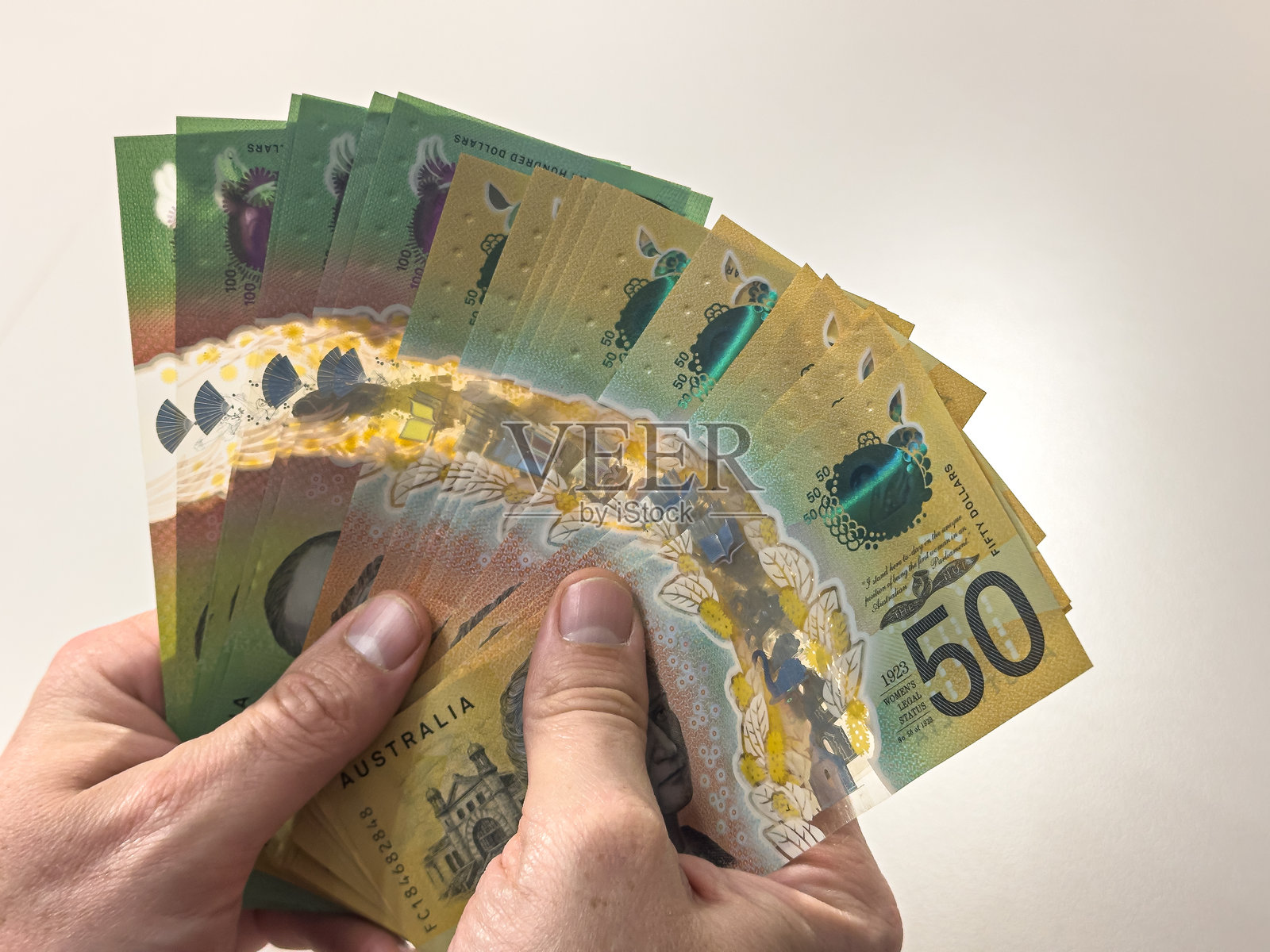 一个男人手中仔细数着新的50和100澳元钞票。储蓄的金钱概念。照片摄影图片