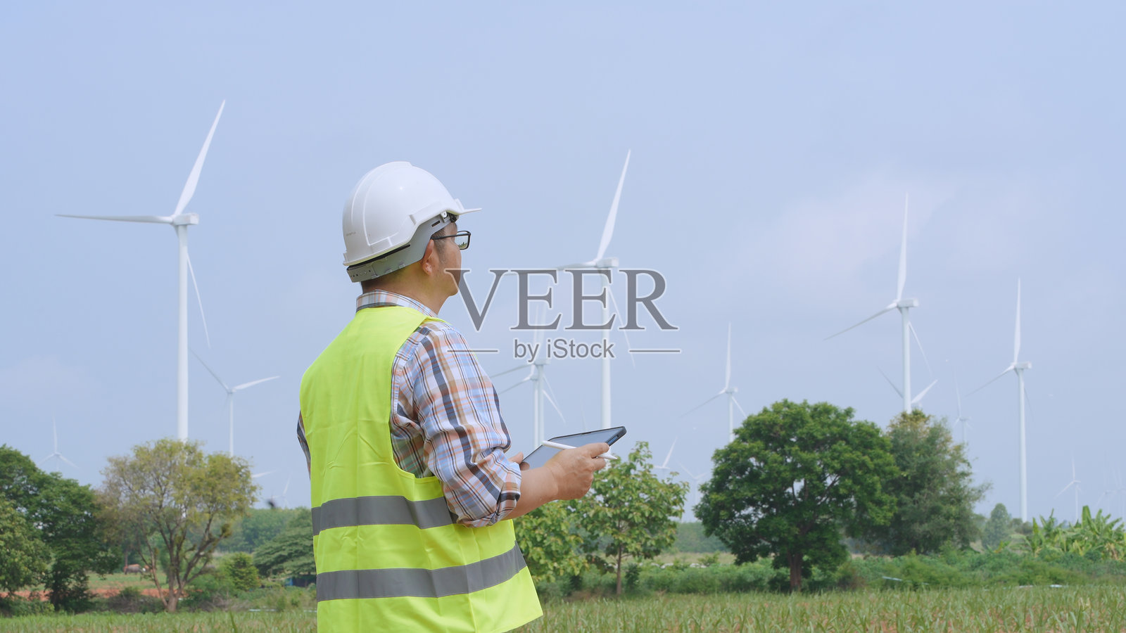 工程师在风力发电场使用笔记本电脑工作，致力于可再生清洁能源的电力生产照片摄影图片