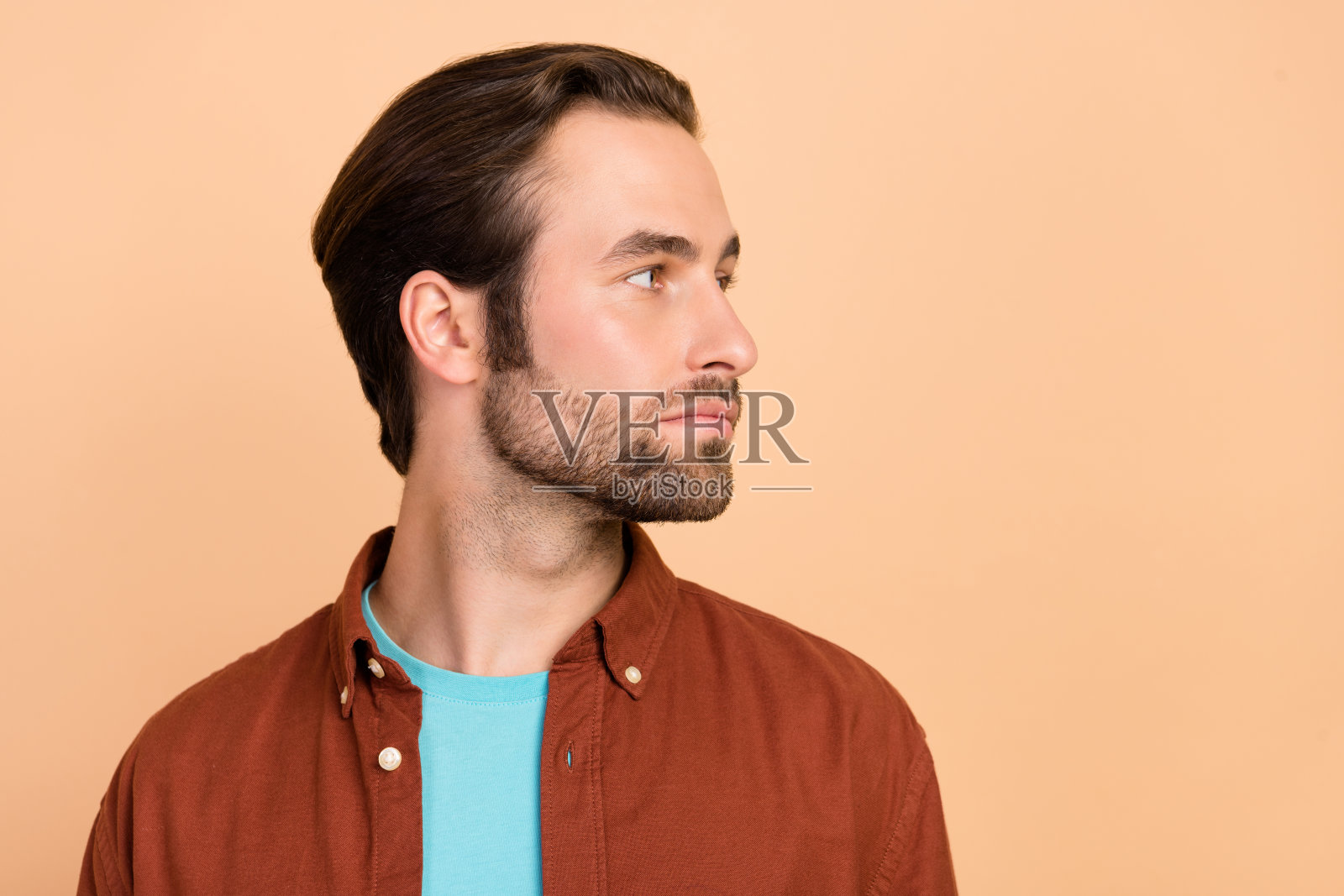 专注的男人凝视空旷的空间，准备剃须，穿着休闲服，背景为米色。照片摄影图片