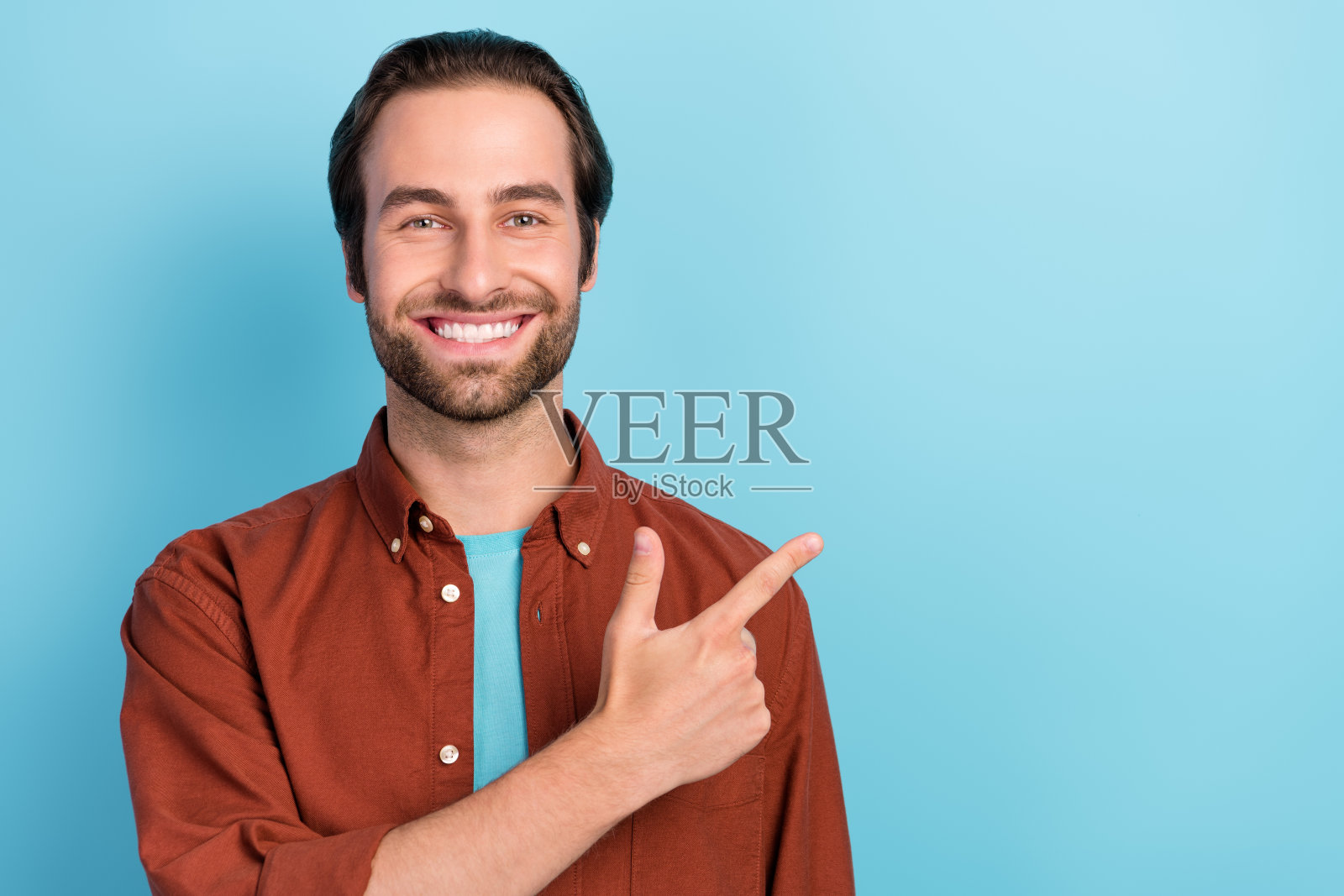 阳光帅气的男性指着空白处，宣传产品优惠，背景为蓝色。照片摄影图片