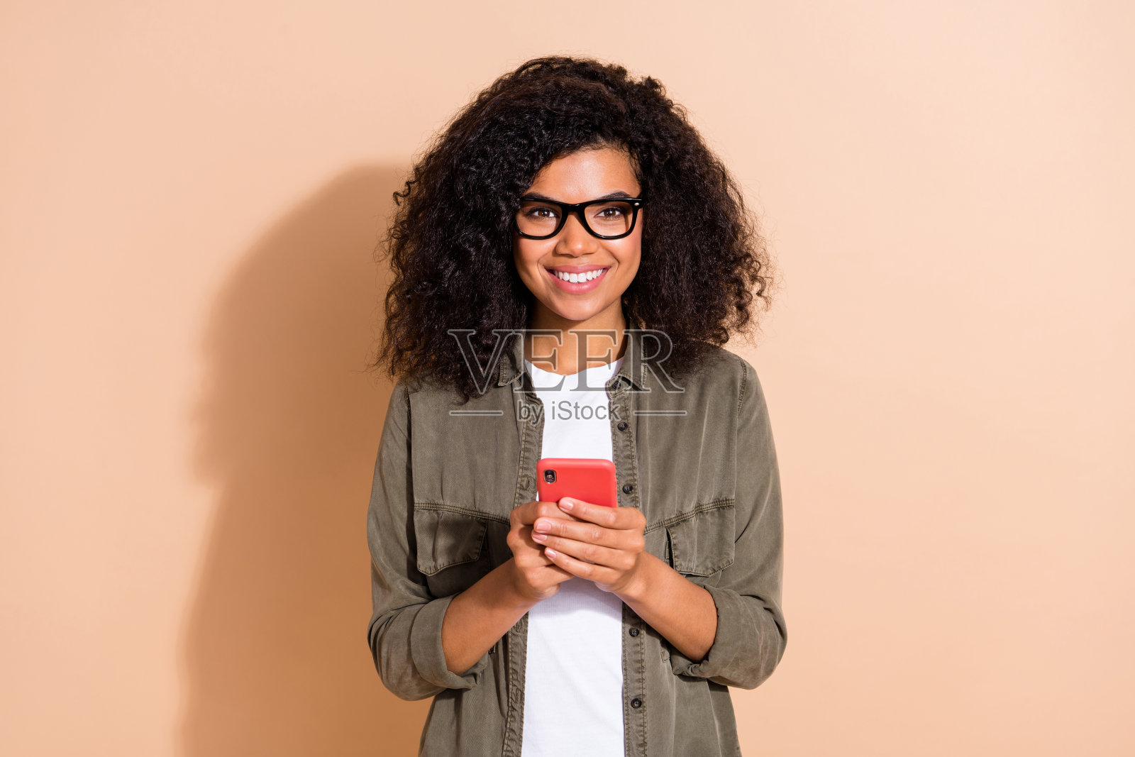 年轻非洲女性使用智能手机按钮应用程序订阅4G，背景为米色。照片摄影图片