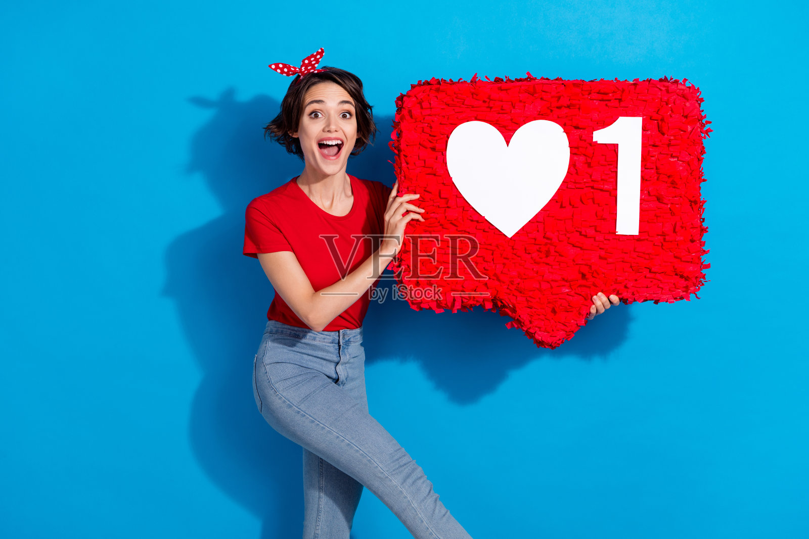 年轻快乐的女孩高兴地作为热门应用用户，隔离在蓝色背景上，分享反馈。照片摄影图片