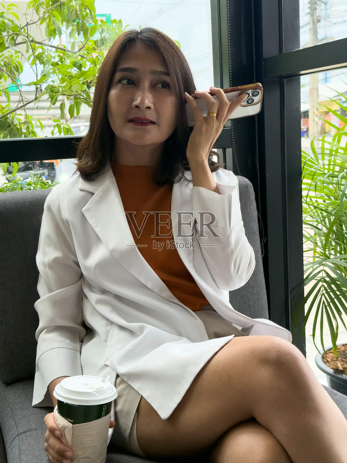 女性坐在咖啡馆，使用智能手机上的虚拟语音助手，放松心情，享受假期生活，浏览社交媒体。照片摄影图片