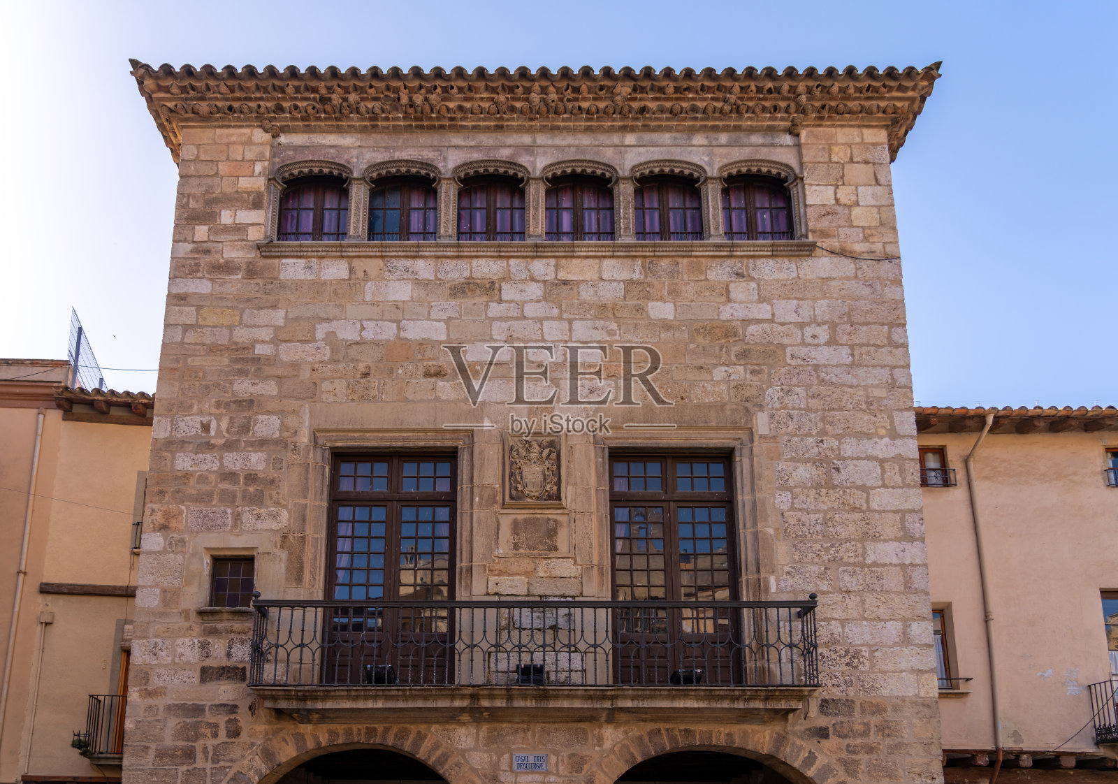 蓝天下有窗户和阳台的石建筑外立面。照片摄影图片