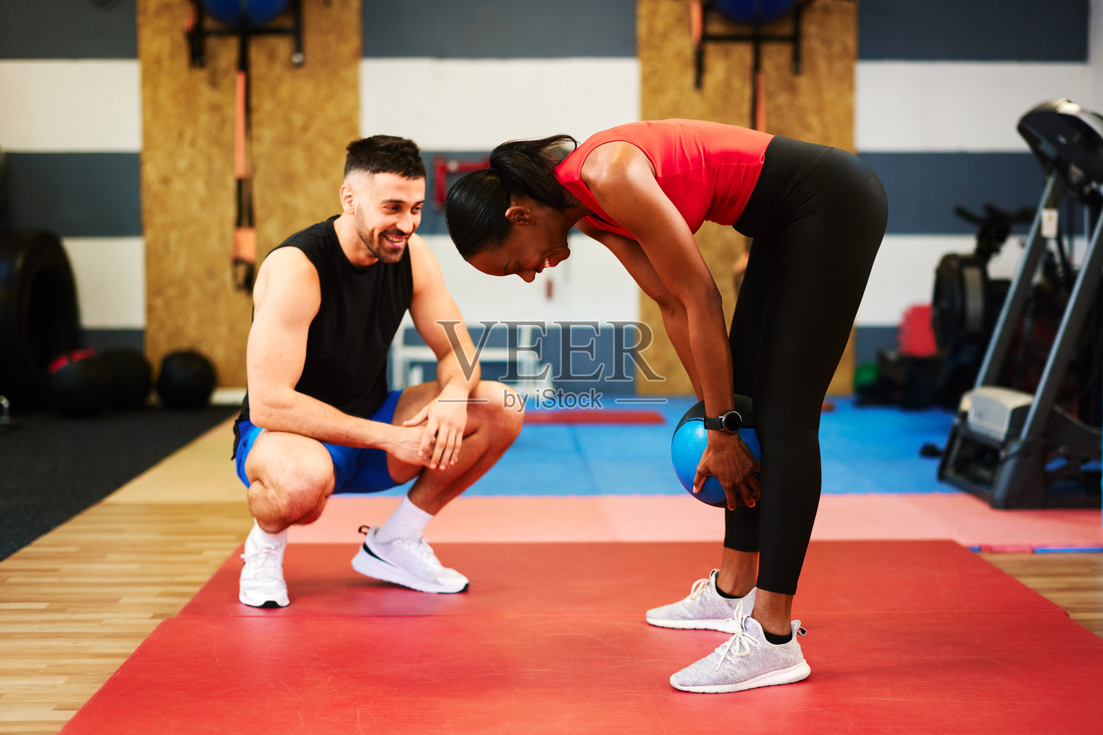 私人教练在健身房指导一位女性使用药球锻炼，倡导健身和健康生活方式照片摄影图片