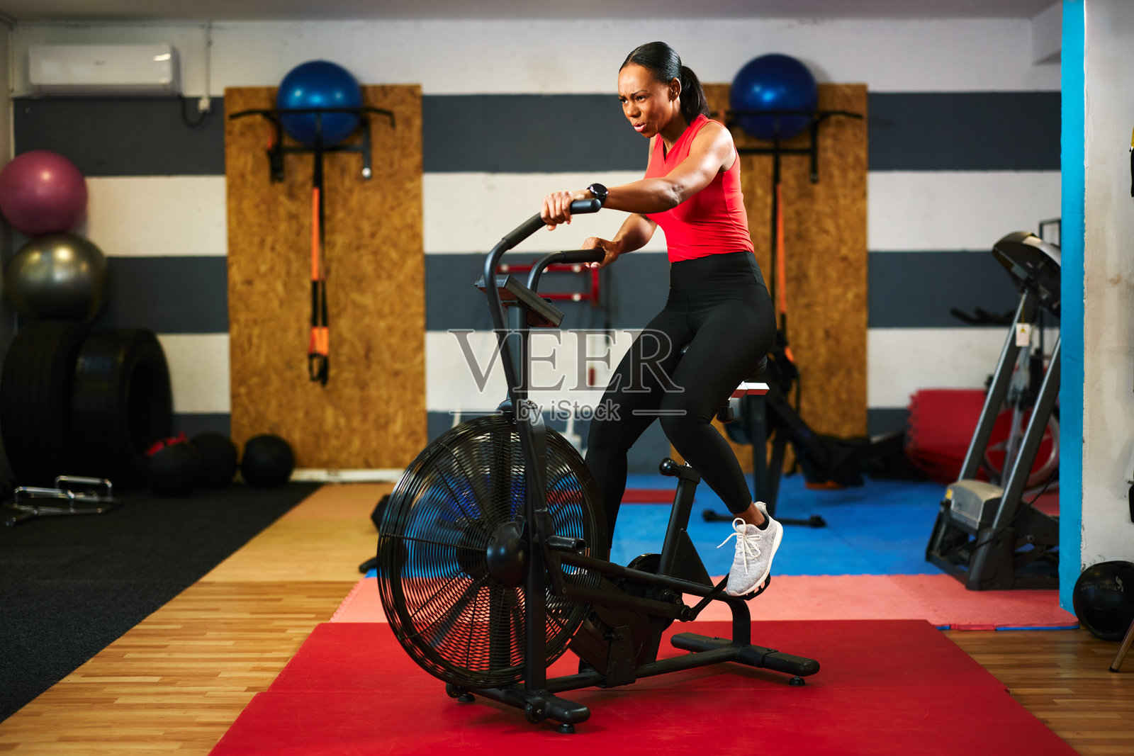 坚定的女运动员在健身房进行高强度有氧运动，使用空气自行车照片摄影图片