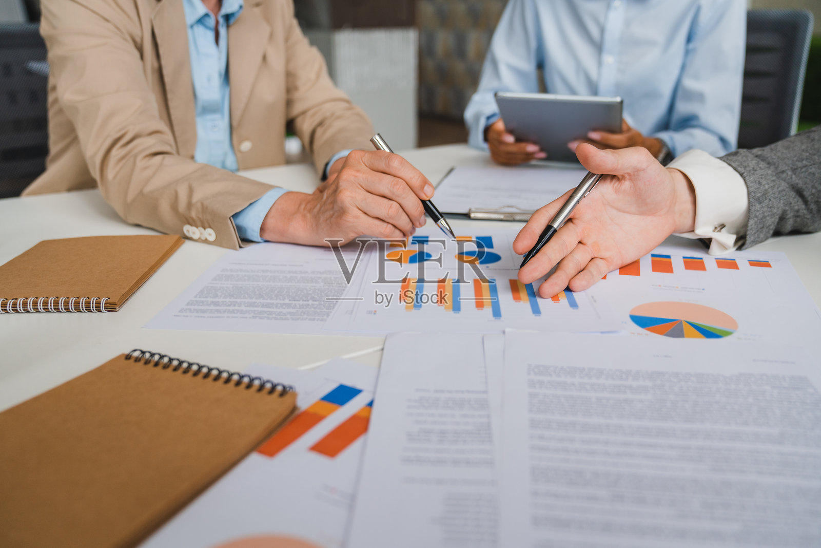 团队合作过程。商务人士在会议中讨论时指着商业文件。商务人士会议上解释财务图表数据和市场计划。照片摄影图片