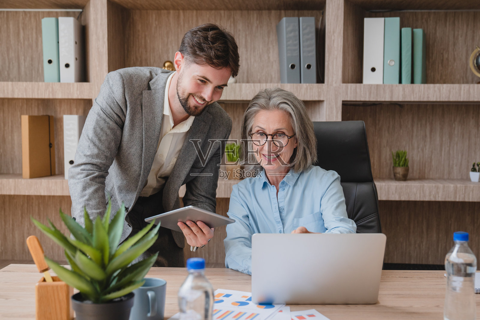 快乐忙碌的高管们在办公室一起工作。经理向同事展示财务结果。两位专业的商务男女在公司会议上使用笔记本电脑。照片摄影图片