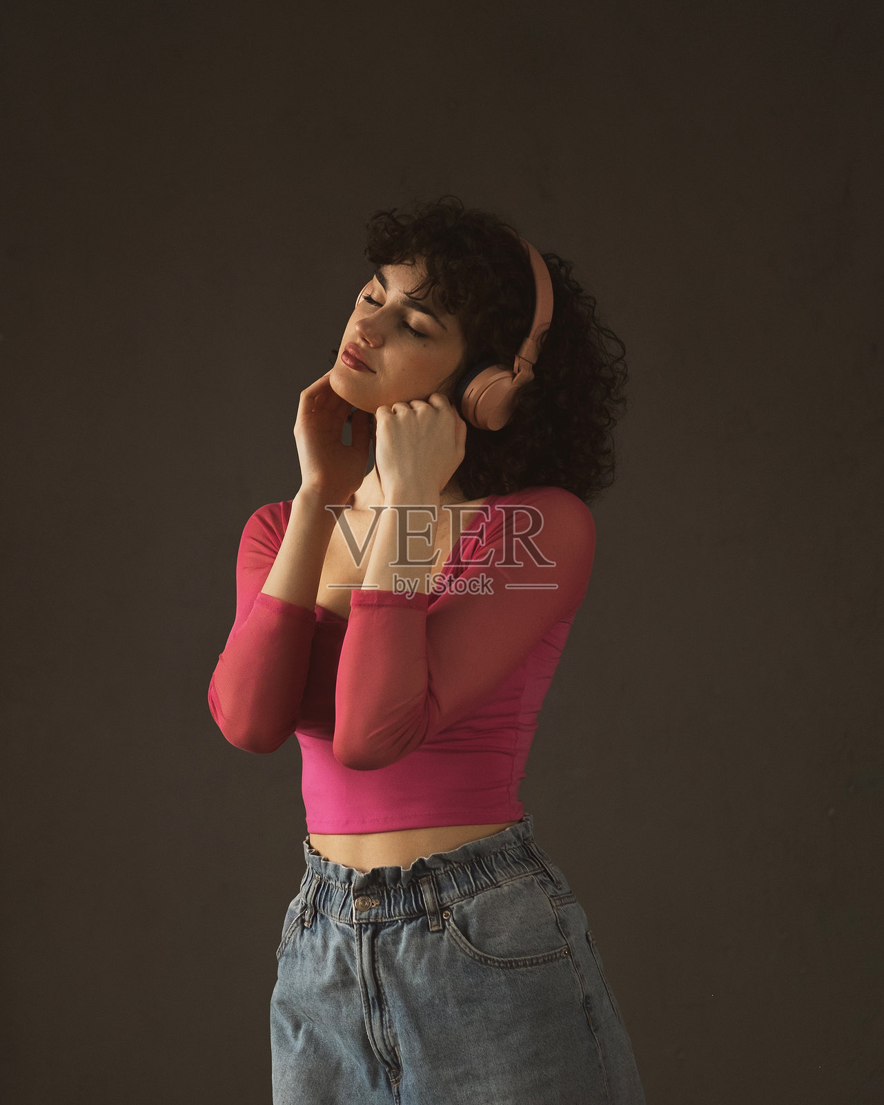 生活方式与人们的概念：年轻的卷发女性戴着耳机，闭着眼睛微笑着听音乐照片摄影图片