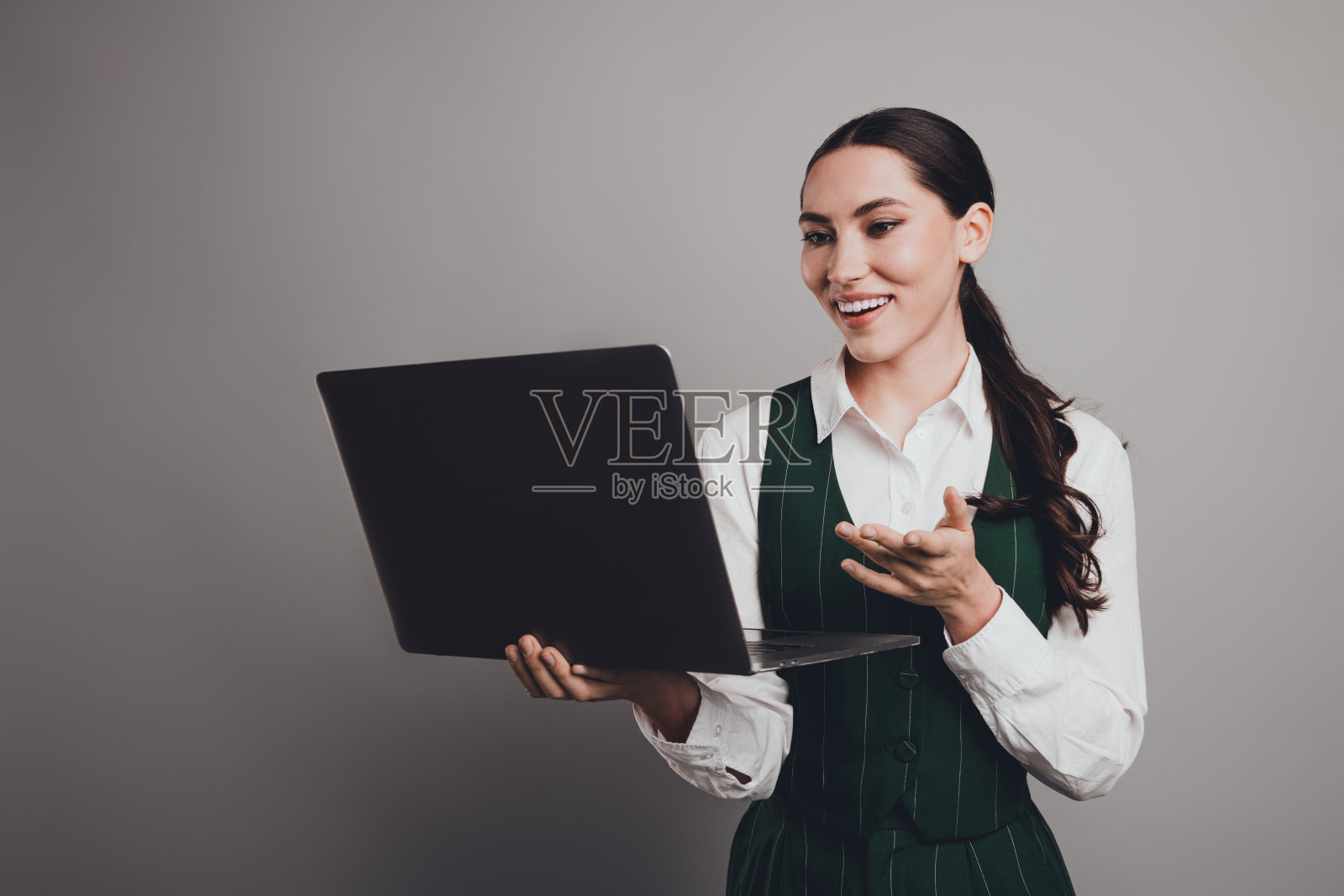 优雅自信的女商人在现代专业环境中手持笔记本电脑照片摄影图片