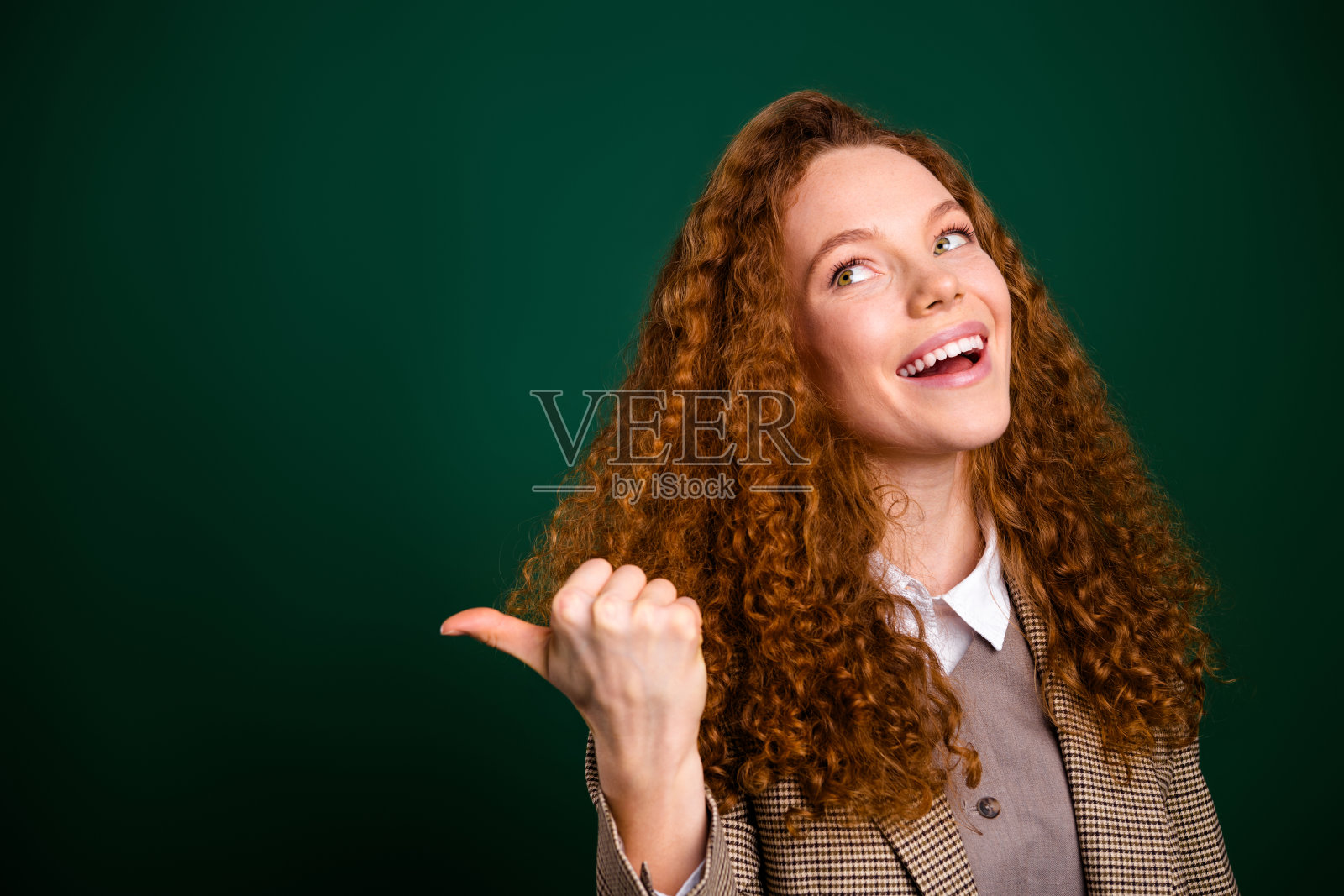 充满活力的职业女性在绿色背景下自信地竖起大拇指，展现出愉悦的态度和时尚的优雅。照片摄影图片