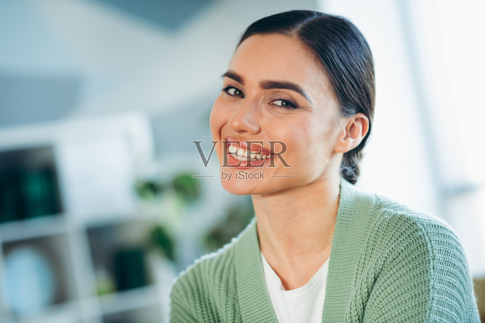 微笑的年轻女性穿着休闲服，在舒适的客厅里享受自然光照的美好时光照片摄影图片