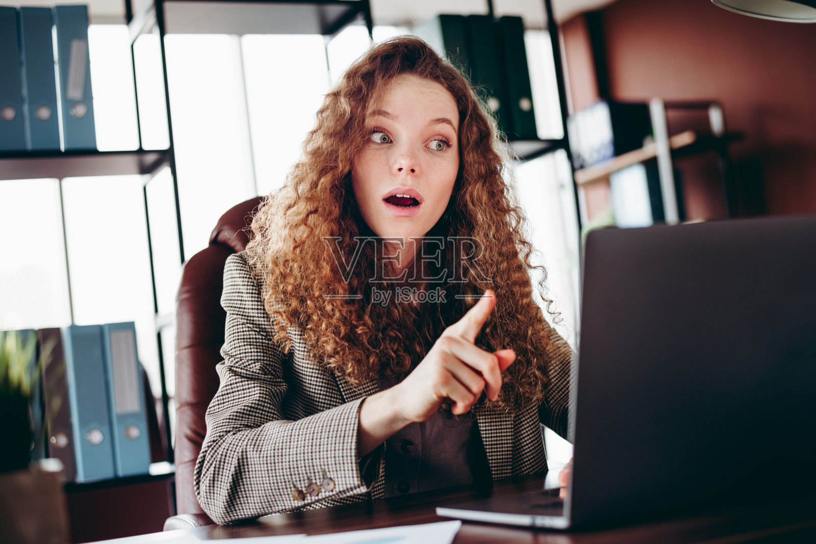 负责的工作人员在办公室桌前工作时，对消息感到惊讶的年轻女性反应。照片摄影图片