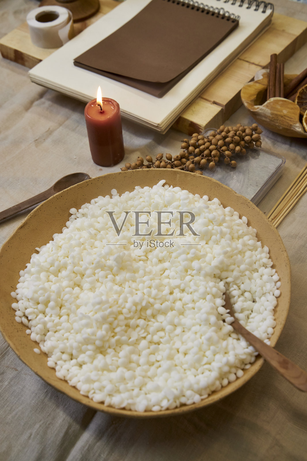 一个创意工作空间，里面有工具、蜡、干花和一个陶瓷碗，正在制作手工蜡烛的过程中。一个温馨而美观的DIY时刻。照片摄影图片