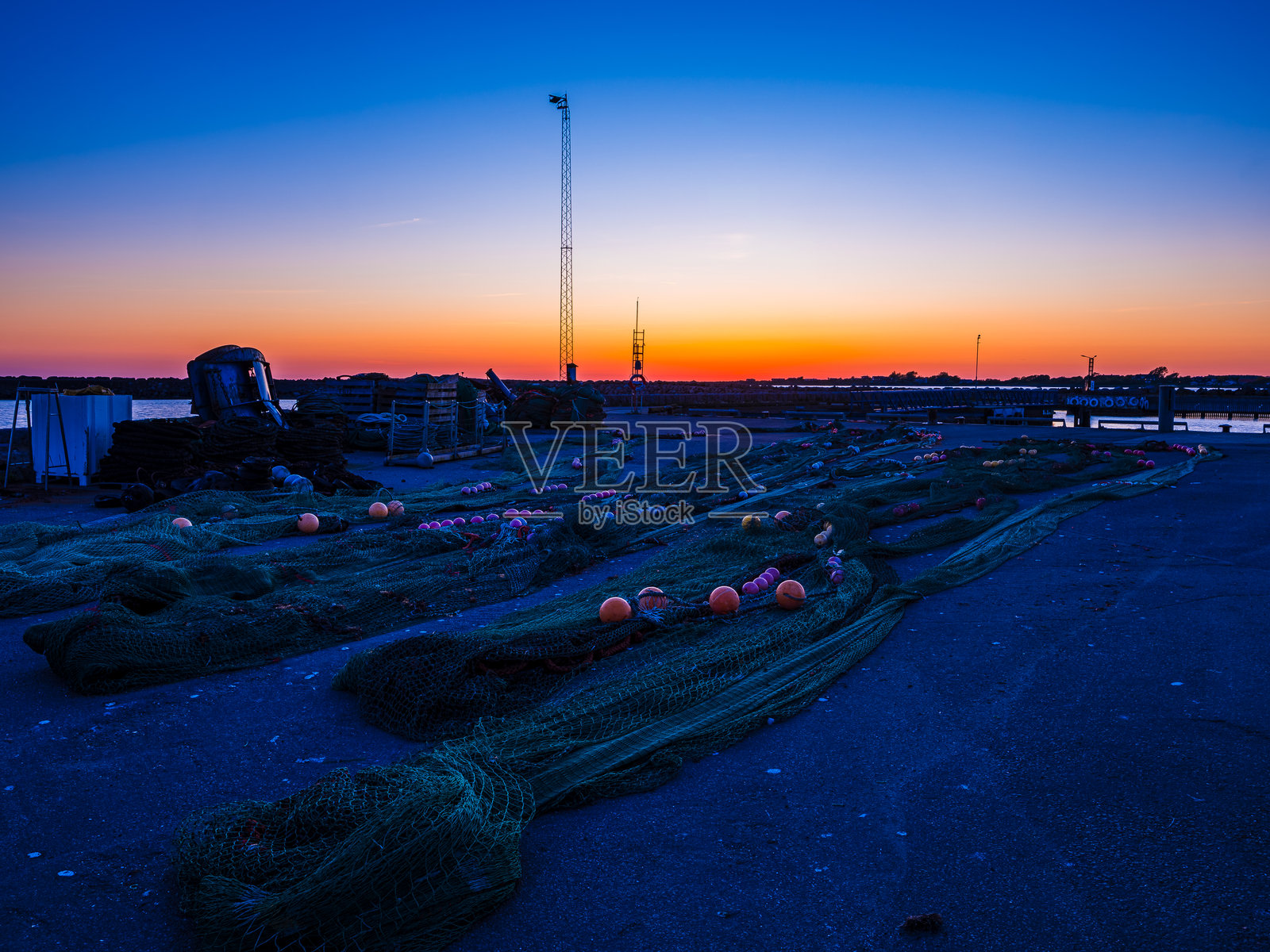 渔网设备沿着码头排放，夕阳下瑞典宁静的港口。照片摄影图片
