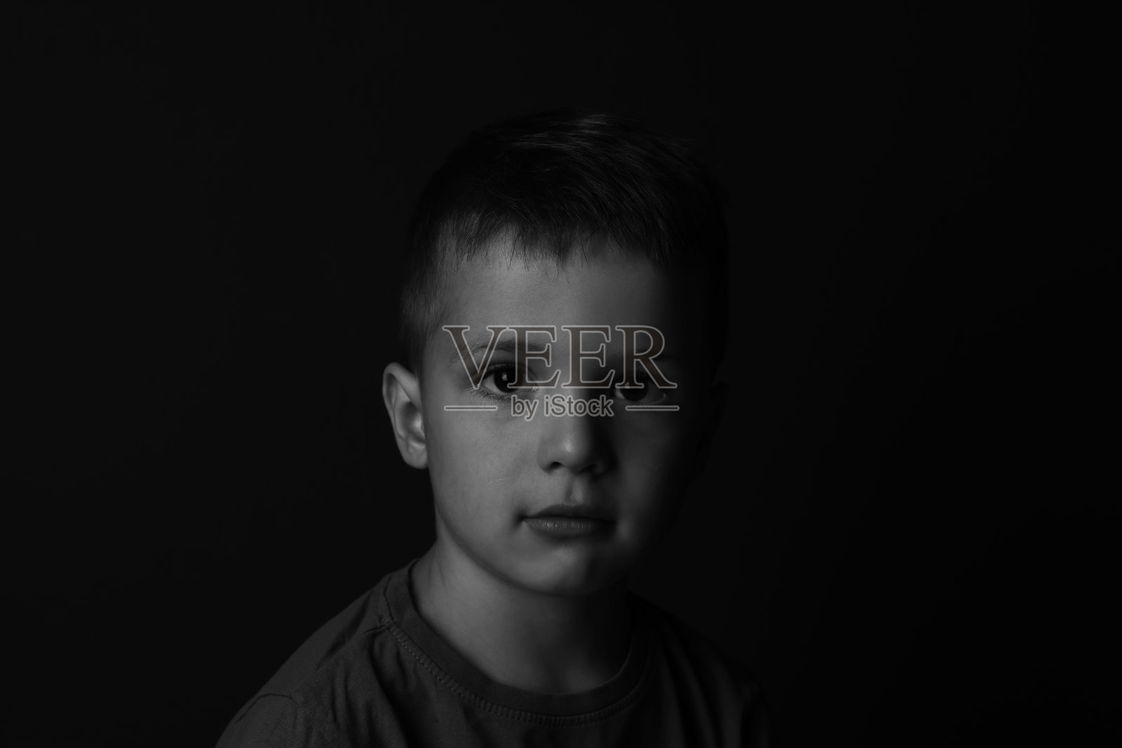 黑暗背景下悲伤的小男孩肖像。黑白效果。照片摄影图片