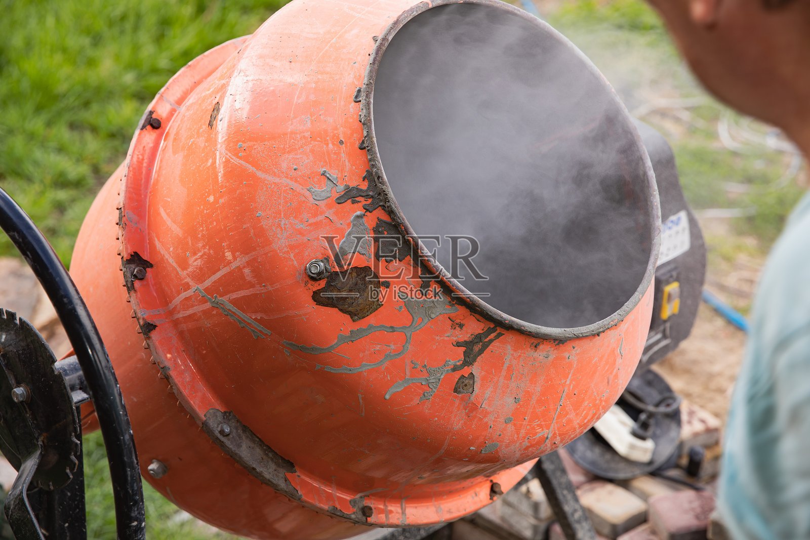 旧水泥搅拌机，鼓内冒出蒸汽照片摄影图片