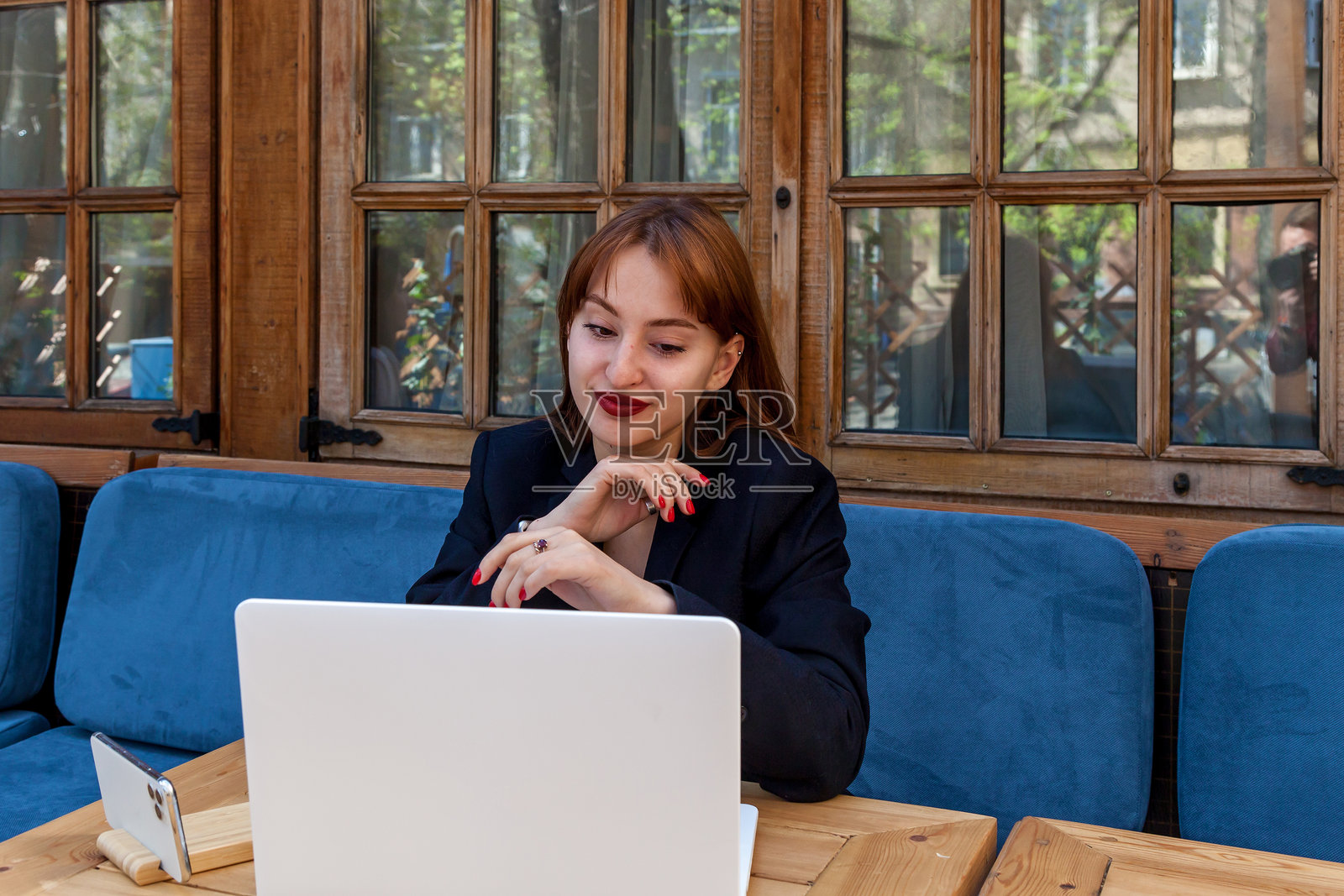 微笑的女性在舒适的户外咖啡馆使用笔记本电脑照片摄影图片